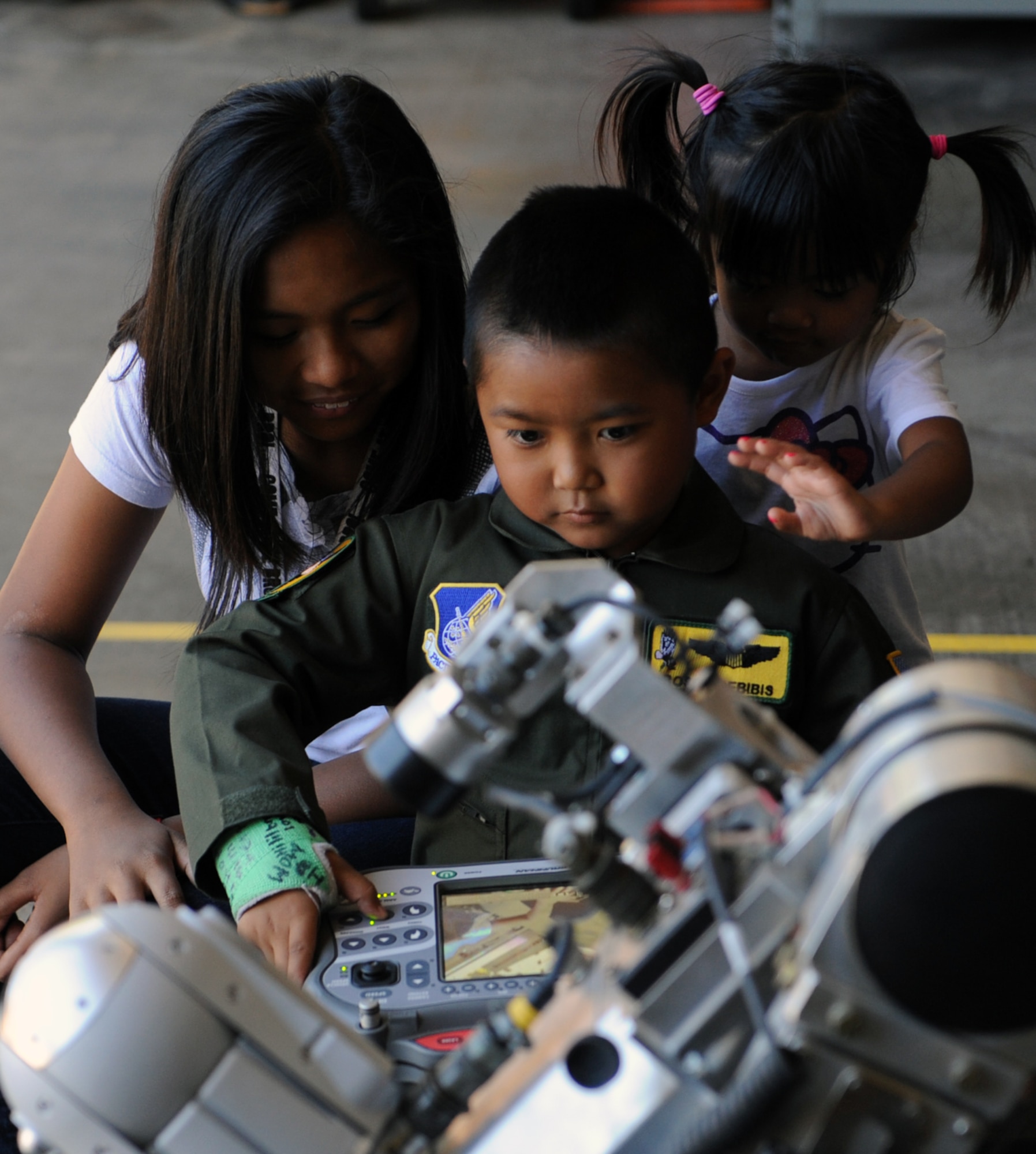 Rosco Rebibis (center), a patient at Kapiolani Medical battling acute lymphoblastic leukemia, operates a bomb robot with the help his sisters Racidy (left) and Reesa June 29 as part of the Pilot for a Day program at Joint Base Pearl Harbor-Hickam, Hawaii. ALL is a cancer of the blood and bone marrow and is the most common type of cancer in children. (U.S. Air Force photo by Staff Sgt. Nathan Allen)