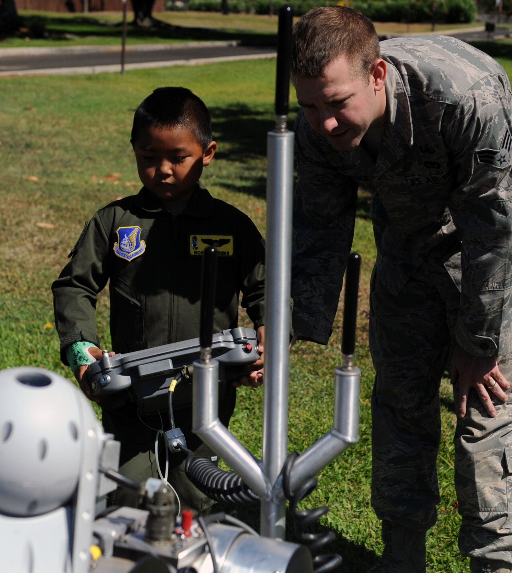 Rosco Rebibis, a patient at Kapiolani Medical battling acute lymphoblastic leukemia, operates a bomb robot with the help of Senior Airman Ben Hancock, 647th Civil Engineer Squadron munitions journeyman June 29 as part of the Pilot for a Day program at Joint Base Pearl Harbor-Hickam, Hawaii. ALL is a cancer of the blood and bone marrow and is the most common type of cancer in children. (U.S. Air Force photo by Staff Sgt. Nathan Allen)