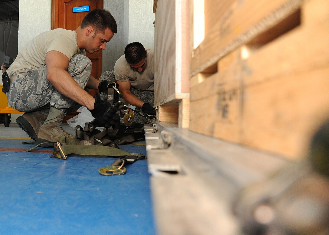 Staff Sgt. Angel Ortega (left), 571st Mobility Support Advisory Squadron air transportation air advisor, and Staff Sgt. Peter Salinas, 571st MSAS air transportation air advisor, secure cargo straps onto a pallet before loading it onto an aircraft during an Air Mobility Command Building Partner Capacity mission at General Alberto Pauwels Rodriguez Air Base in Barranquilla, Colombia, June 27.  (U.S. Air Force photo by Tech. Sgt. Lesley Waters) 