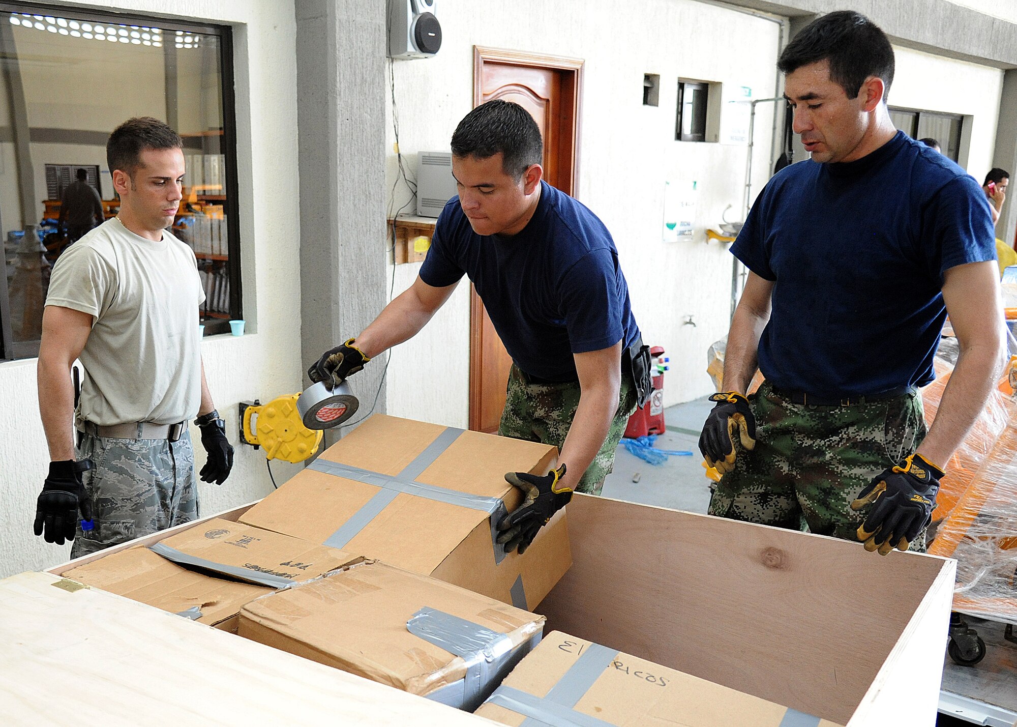 Staff Sgt. Angel Ortega, 571st Mobility Support Advisory Squadron air transportation air advisor, looks on as members of the Colombian air force prepares a wooden box for palletizing during an Air Mobility Command Building Partner Capacity mission at General Alberto Pauwels Rodriguez Air Base in Barranquilla, Colombia, June 27.  (U.S. Air Force photo by Tech. Sgt. Lesley Waters)