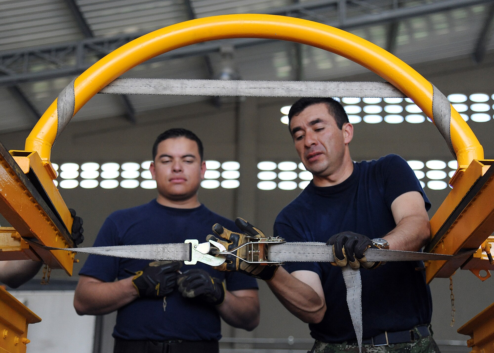 Members of the Colombian air force use a cargo strap to secure loose equipment before loading it onto an aircraft during an Air Mobility Command Building Partner Capacity mission at General Alberto Pauwels Rodriguez Air Base in Barranquilla, Colombia, June 27.  (U.S. Air Force photo by Tech. Sgt. Lesley Waters)