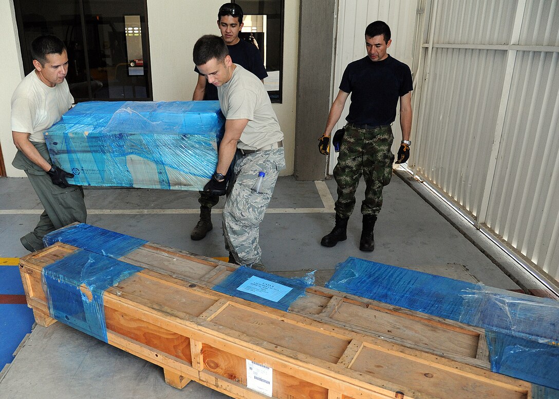 Staff Sgt. Javier Borges (left), 571st Mobility Support Advisory Squadron loadmaster air advisor, and Staff Sgt. Angel Ortega, 571st MSAS air transportation air advisor, assist the Colombian air force build pallets during an Air Mobility Command Building Partner Capacity mission at General Alberto Pauwels Rodriguez Air Base in Barranquilla, Colombia, June 27.  (U.S. Air Force photo by Tech. Sgt. Lesley Waters)