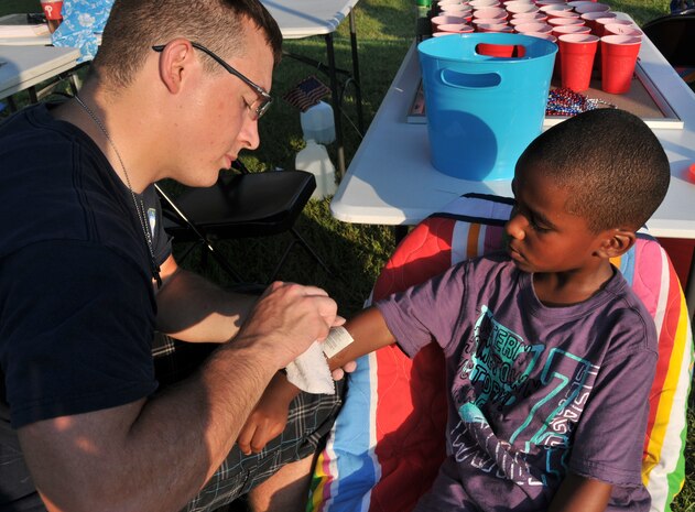 Petty Officer 3rd Class Levi Brazille, a graduate from Navy Nuclear Power Training Command, places a temporary tattoo on Elijah Walls June 29, during the 2012 Freedom Fest at Marrington Plantation at Joint Base Charleston – Weapons Station. Walls is the son of Master Sgt. Jadirra Walls, 437th Maintenance Squadron first sergeant and Tech. Sgt. Darnell Walls from the 628th Civil Engineer Squadron fire department. Nearly 1,500 Sailors, Airmen, civilians and their families attended the fest which included food, drinks, festival rides, music and fireworks. (U.S. Air Force photo/Airman 1st Class Jared Trimarchi)