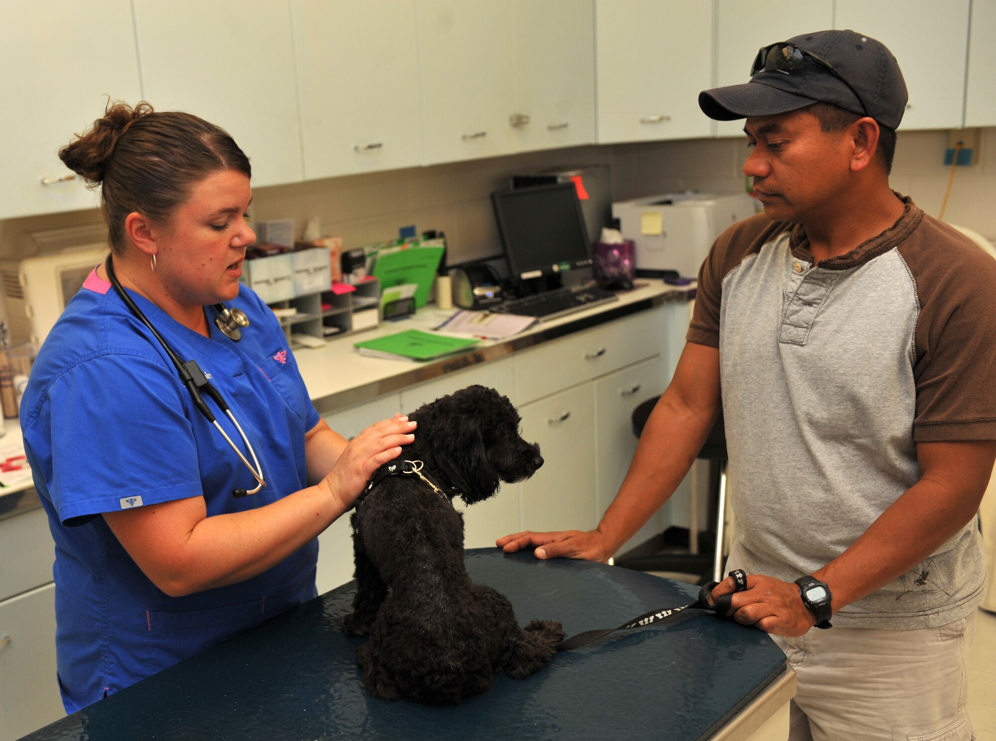 Dr. Erin Hiskett, McConnell Veterinary Clinic veterinarian, explains the health of Maximus, a poodle mix, to owner Tech. Sgt. Richard Tagalicud, 22nd Civil Engineering Squadron electrician June 28, 2012, McConnell Air Force Base, Kan. Tagalicud took Max in for his biannual check up with the clinic to see if any new medications were necessary to keep his health at a maximum. (U.S. Air Force photos/ Airman 1st Class Victor Caputo)