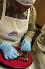MINOT AIR FORCE BASE, N.D. -- Senior Airman Antona Gaskins, 741st Missile Squadron missile chef, garnishes a steak with grilled bacon during the “Warrior Chef 2012” competition, here June 27. The annual competition gave Team Minot chefs the chance to demonstrate their skills and be recognized for their talents in a friendly environment. It was a true test of culinary mastery as a team from each wing went head-to-head in a 45-minute, ultimate dish showdown. (U.S. Air Force photo/Senior Airman Desiree W. Esposito)
