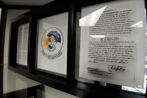 A frame containing the 3d Weather Squadron’s patch and signed contract showing the design, which was licensed from the Walt Disney Company to the government for $1, sits in the heritage room of the 3d WS, Fort Hood, Texas, June 25, 2012. The patch shows the character Cupid from the Disney movie “Fantasia” jotting down the weather forecast while sitting on a cloud between sun and rain. He is wearing a “Sherlock Holmes” hat symbolizing the unit’s mission of weather investigation and prediction.(U.S. Air Force photo by Staff Sgt. Joshua J. Garcia/Released)