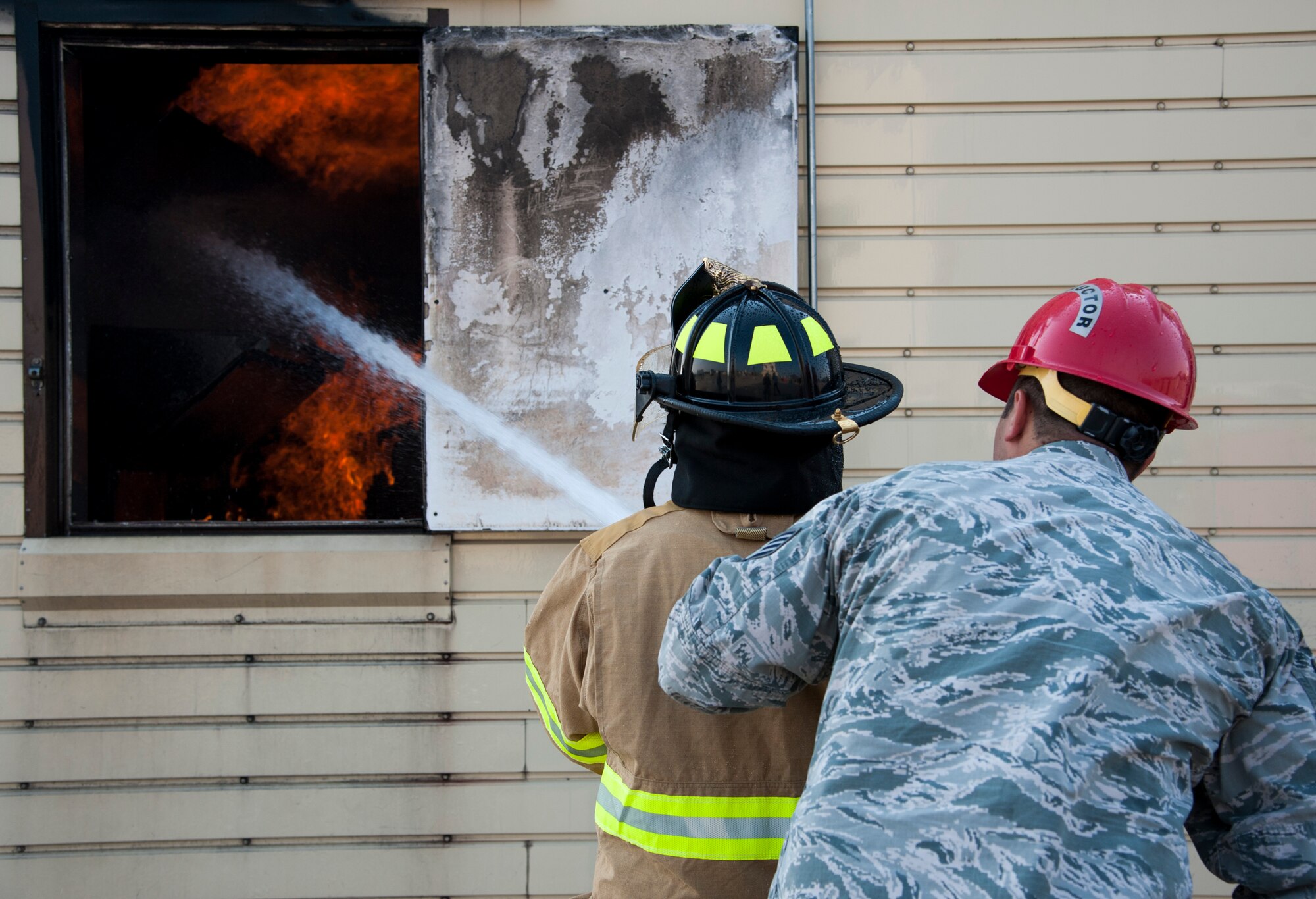 GOODFELLOW AIR FORCE BASE, Texas-- Maxwell “Trey” Pons III, Honorary Air Force firefighter, extinguishes a simulated interior fire with the help of Staff Sgt. Michael Barbett, 312th Training Squadron instructor, at the Louis F. Garland DOD Fire Academy June 28. Pons, who is autistic, sight impaired and hearing-impaired, accomplished his dream to become a firefighter by going through each training block in a day at the Fire Academy. (U.S. Air Force photo/Airman 1st Class Michael Smith)