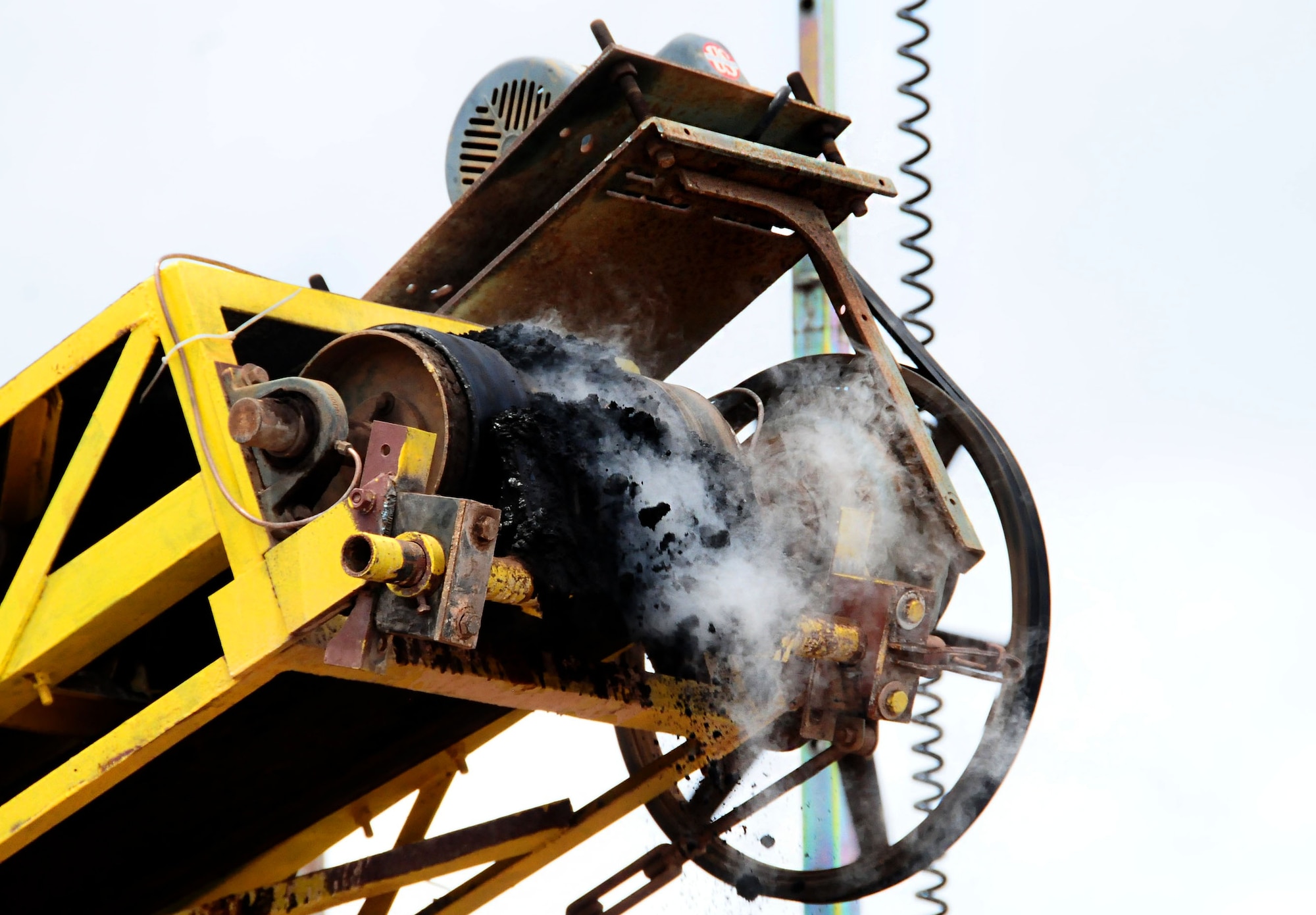 Scorching soil, fresh from the incinerator, falls from the conveyor belt into a decontaminated heap at the thermal desorption site, June 29. Thermal desorption is a physical separation process that is designed not to destroy organic material. (U.S. Air Force photo by Airman 1st Class Marianique Santos/Released)