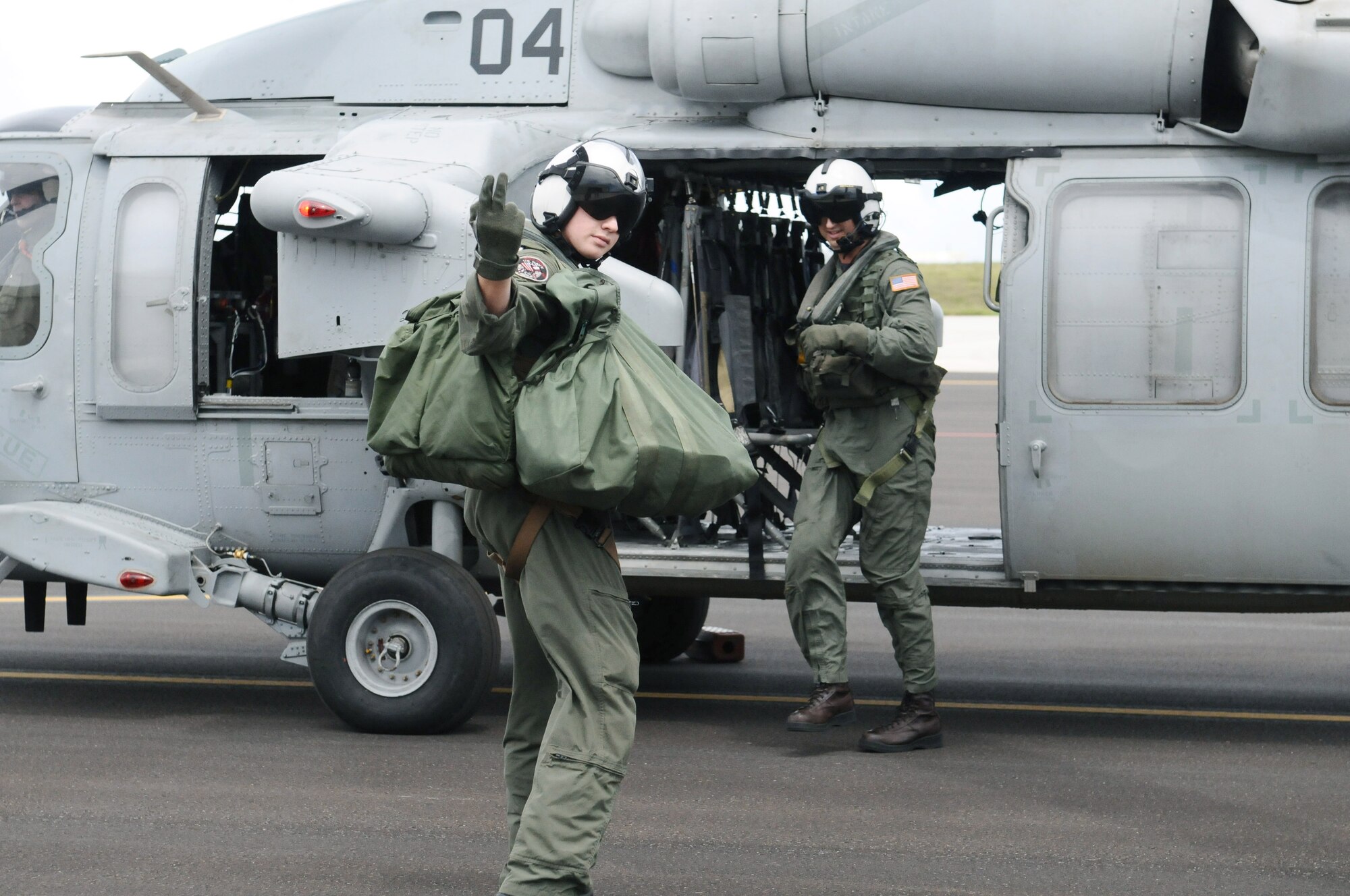 Naval Air Crewman 3rd Class Zack Schwab, Helicopter Sea Combat Two-Five search and rescue swimmer, motions to servicemembers preparing to board an incentive flight June 13. HSC-25 is tasked with supporting seven fleet units in the Western Pacific, Indian Ocean, North Arabian Sea, and Persian Gulf. (U.S. Air Force photo/Airman 1st Class Mariah Haddenham/Released)

