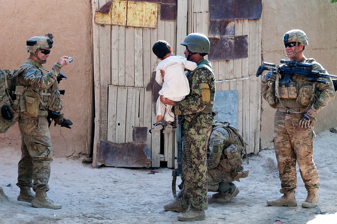 U.S. Army Spc. Harley Young, left, photographs an Afghan soldier posing with a village boy while on patrol in Muqor in Afghanistan's Ghazni province, June 27, 2012. 