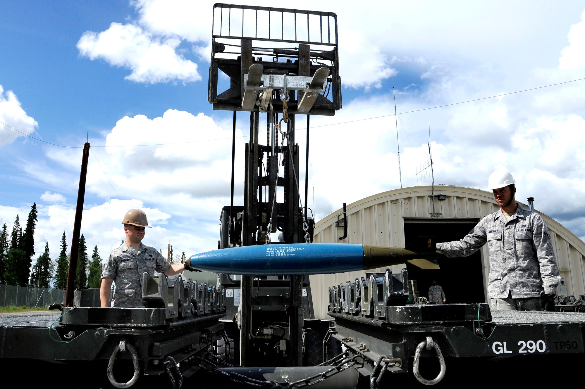U.S. Air Force Senior Airman Garret Bosanko and Airman 1st Class John Berthold, 51st Munitions Squadron munitions crew chiefs, lower a bomb dummy unit onto a munitions handling unit with a forklift July 2, 2012, Eielson Air Force Base, Alaska. (U.S. Air Force photo/Staff Sgt. Jim Araos)