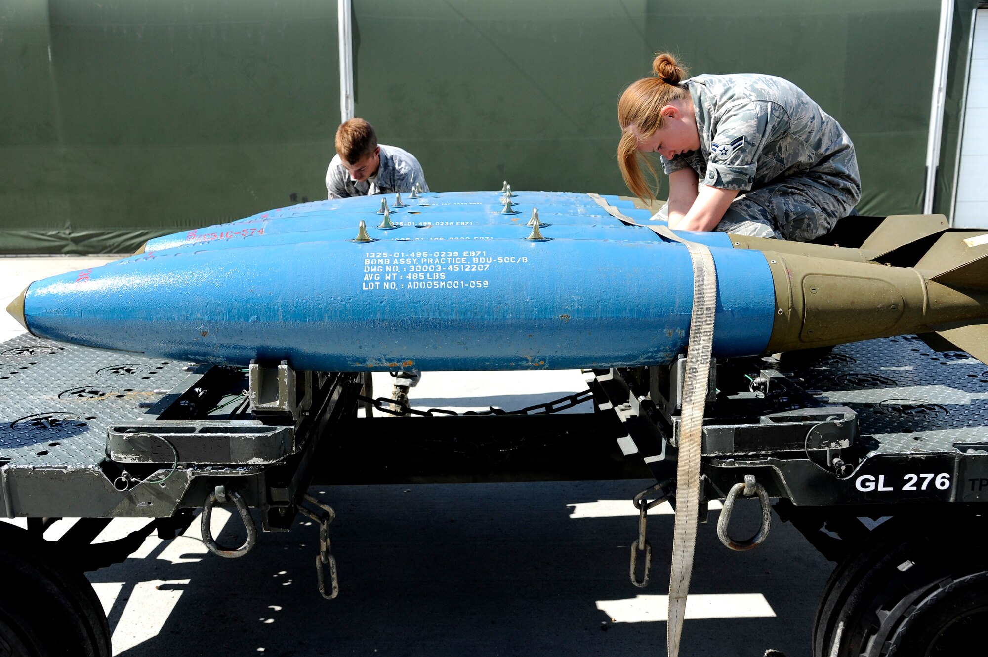 U.S. Air Force Airmen 1st Class John Berthold and Amberlyn Hawkins, 51st Munitions Squadron munitions crew chiefs, strap down bomb dummy units to a munitions handling unit for transport July 2, 2012, Eielson Air Force Base, Alaska. (U.S. Air Force photo/Staff Sgt. Jim Araos)
