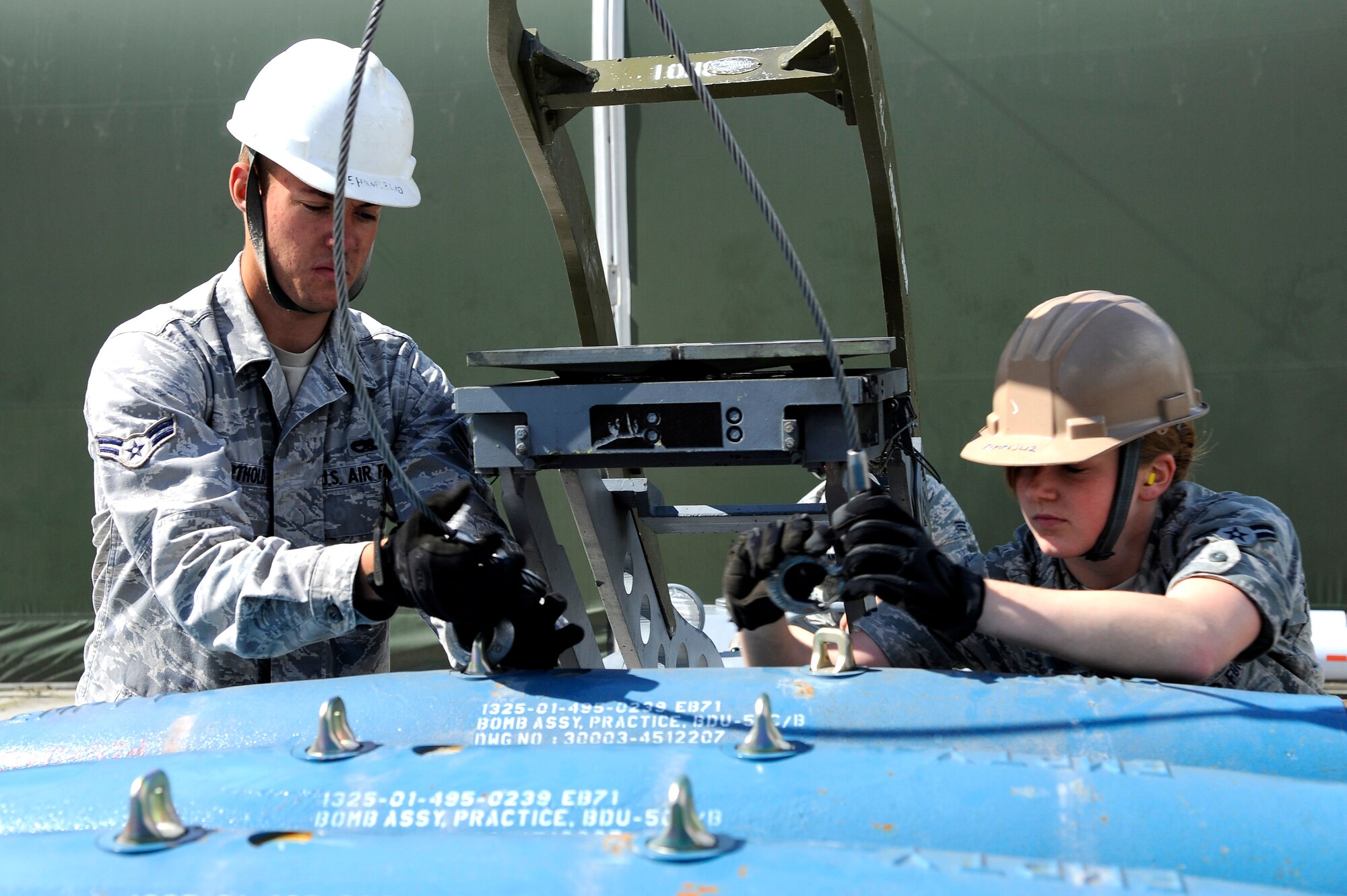 U.S Air Force Airmen 1st Class John Berthold and Amberlyn Hawkins, 51st Munitions Squadron munitions crew chiefs, release the jammer from a bomb dummy unit July 2, 2012, Eielson Air Force Base, Alaska. The jammer, also known as the bomb lift, can transport BDUs weighing up to 500 pounds. (U.S. Air Force photo/Staff Sgt. Jim Araos)