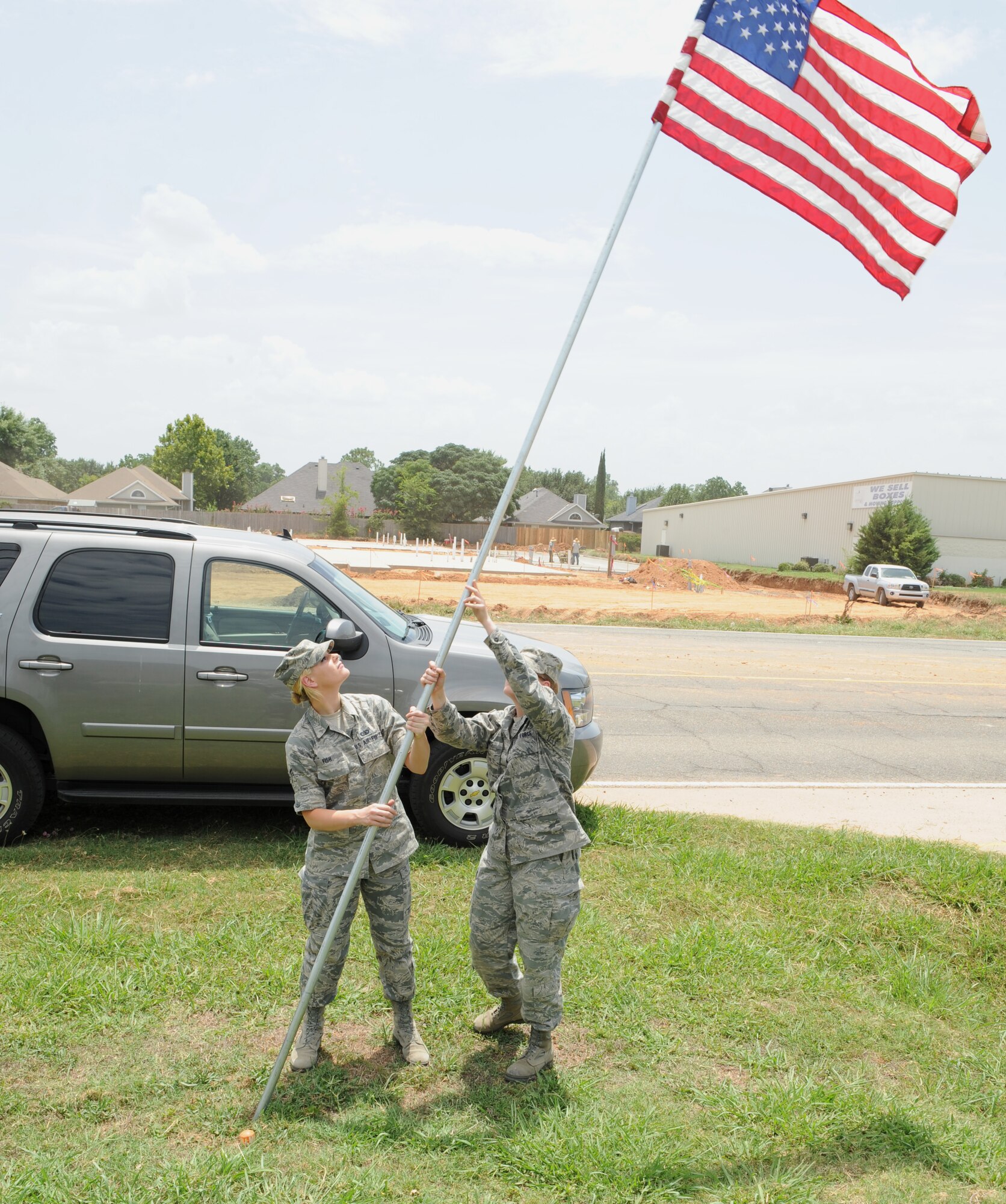 Airmen 1st Class Katharine Fish and Cortni Combs, 608th Air Operations Center intelligence reconnaissance division, raise an American flag near the North Gate on Barksdale Air Force Base, La., July 3. More than 50 flags were raised in celebration of Independence Day. (U.S. Air Force photo/Airman 1st Class Benjamin Gonsier)(RELEASED)
