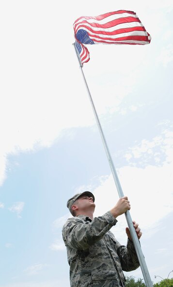 Senior Airman Anthony Kirk, 608th Air Operations Center combat plans division, raises an American flag near the North Gate on Barksdale Air Force Base, La., July 3. More than 50 flags were raised in celebration of Independence Day. (U.S. Air Force photo/Airman 1st Class Benjamin Gonsier)(RELEASED)