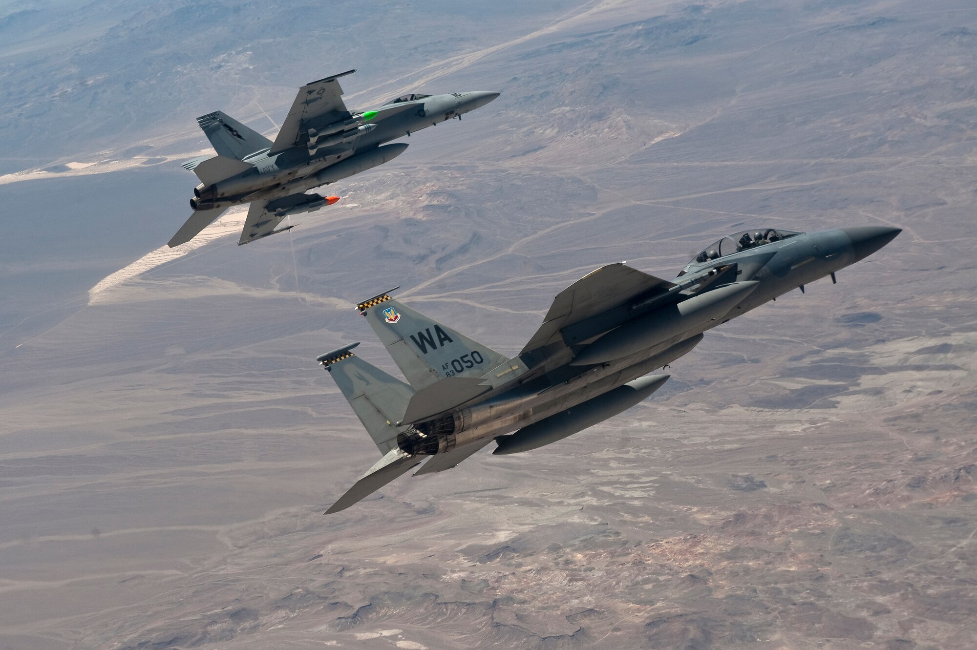 A U.S. Air Force F-15D Eagle, 433rd Weapons School, flies next to a U.S. Navy F/A-18 Super Hornet, Naval Strike and Air Warfare Center, during MIDWAY WHITE III June 26, 2012, over the Nevada Test and Training Range. MIDWAY WHITE III is designed to quantify and improve cave characterization, standardize attack planning processes, and increase weapons employment consistency and lethality. (U.S. Air Force photo by Staff Sgt. Christopher Hubenthal)