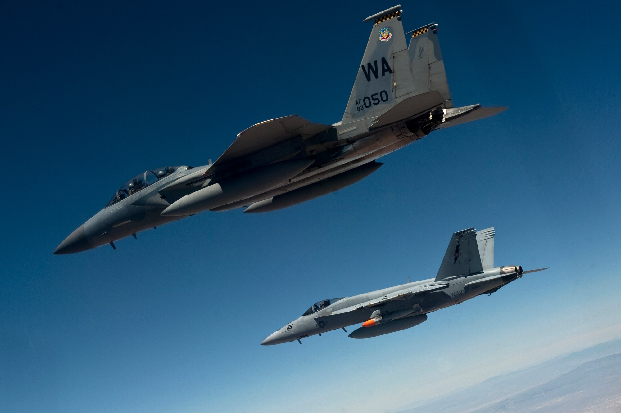 A U.S. Air Force F-15D Eagle, 433rd Weapons School, flies next to a U.S. Navy F/A-18 Super Hornet, Naval Strike and Air Warfare Center, during MIDWAY WHITE III June 26, 2012, over the Nevada Test and Training Range. MIDWAY WHITE III is designed to quantify and improve cave characterization, standardize attack planning processes, and increase weapons employment consistency and lethality. (U.S. Air Force photo by Staff Sgt. Christopher Hubenthal)