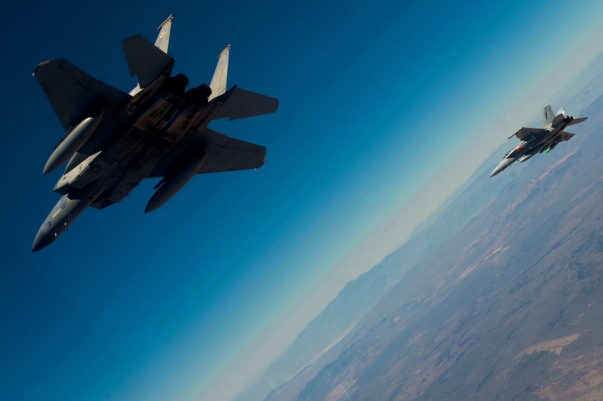 A U.S. Air Force F-15D Eagle, 433rd Weapons School, flies next to a U.S. Navy F/A-18 Super Hornet, Naval Strike and Air Warfare Center, during MIDWAY WHITE III June 26, 2012, over the Nevada Test and Training Range. MIDWAY WHITE is a joint demonstration involving Defense Threat Reduction Agency, the USAF Weapons School, and elements of the Naval Strike and Air Warfare Center. (U.S. Air Force photo by Staff Sgt. Christopher Hubenthal)