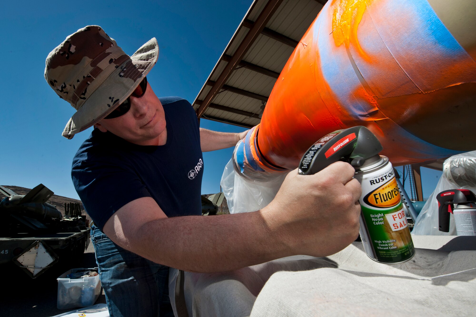 Phillip Taber, USAF Weapons School senior scientist and instructor, paints an inert guided bomb unit during MIDWAY WHITE III June 20, 2012, at Nellis Air Force Base, Nev. The bombs are painted bright colors to track the rate of descent. (U.S. Air Force photo by Airman 1st Class Jason Couillard)