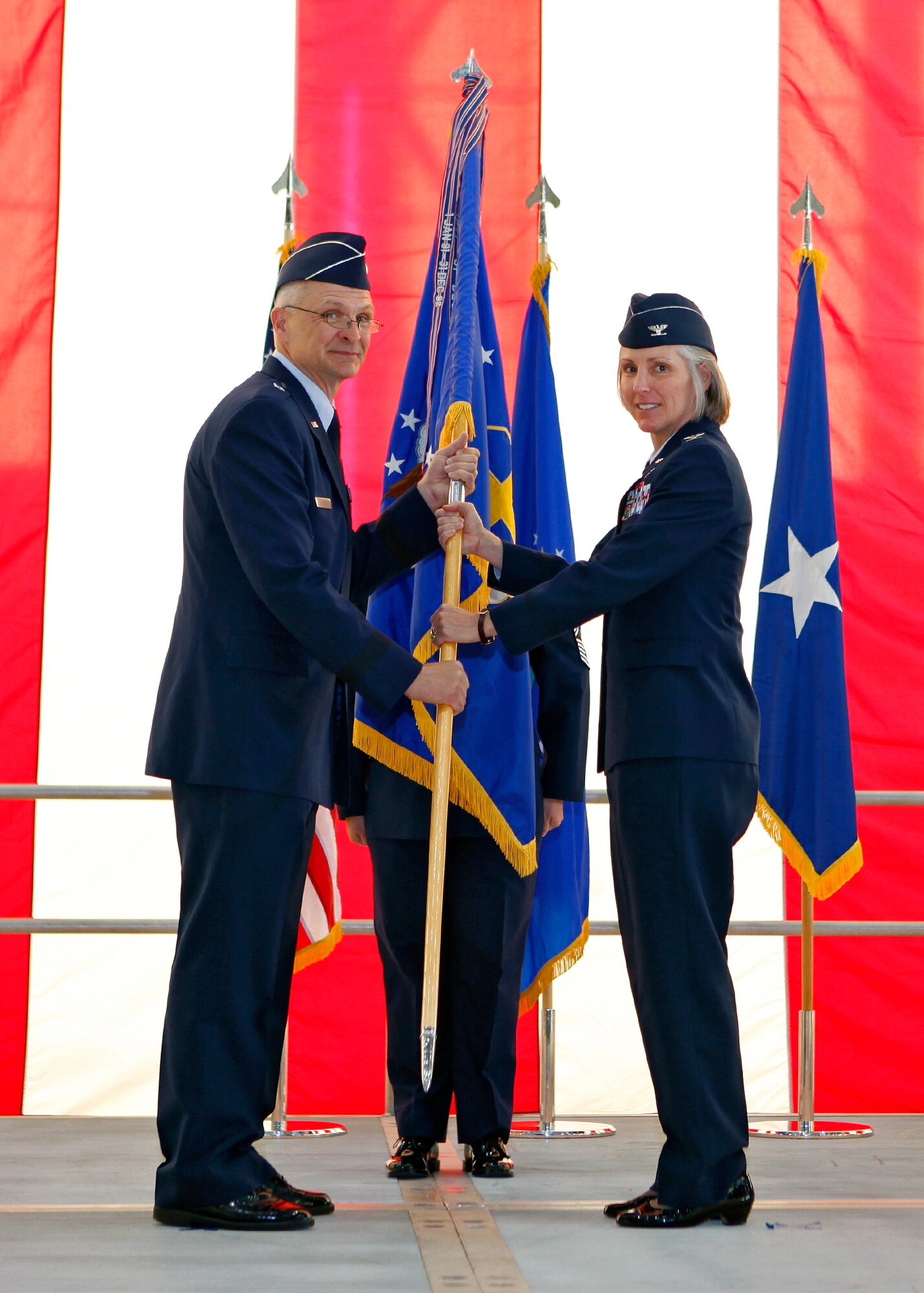 Brig. Gen. Arnold W. Bunch Jr., Air Force Flight Test Center commander, hands Col. Amy V. Arwood the 95th Air Base Wing guideon, signifying the change of command June 29 in Hangar 1600. Arwood assumed command of the 95th ABW from Col. Gregory E. Schwab. (U.S. Air Force Photo by Jet Fabara)