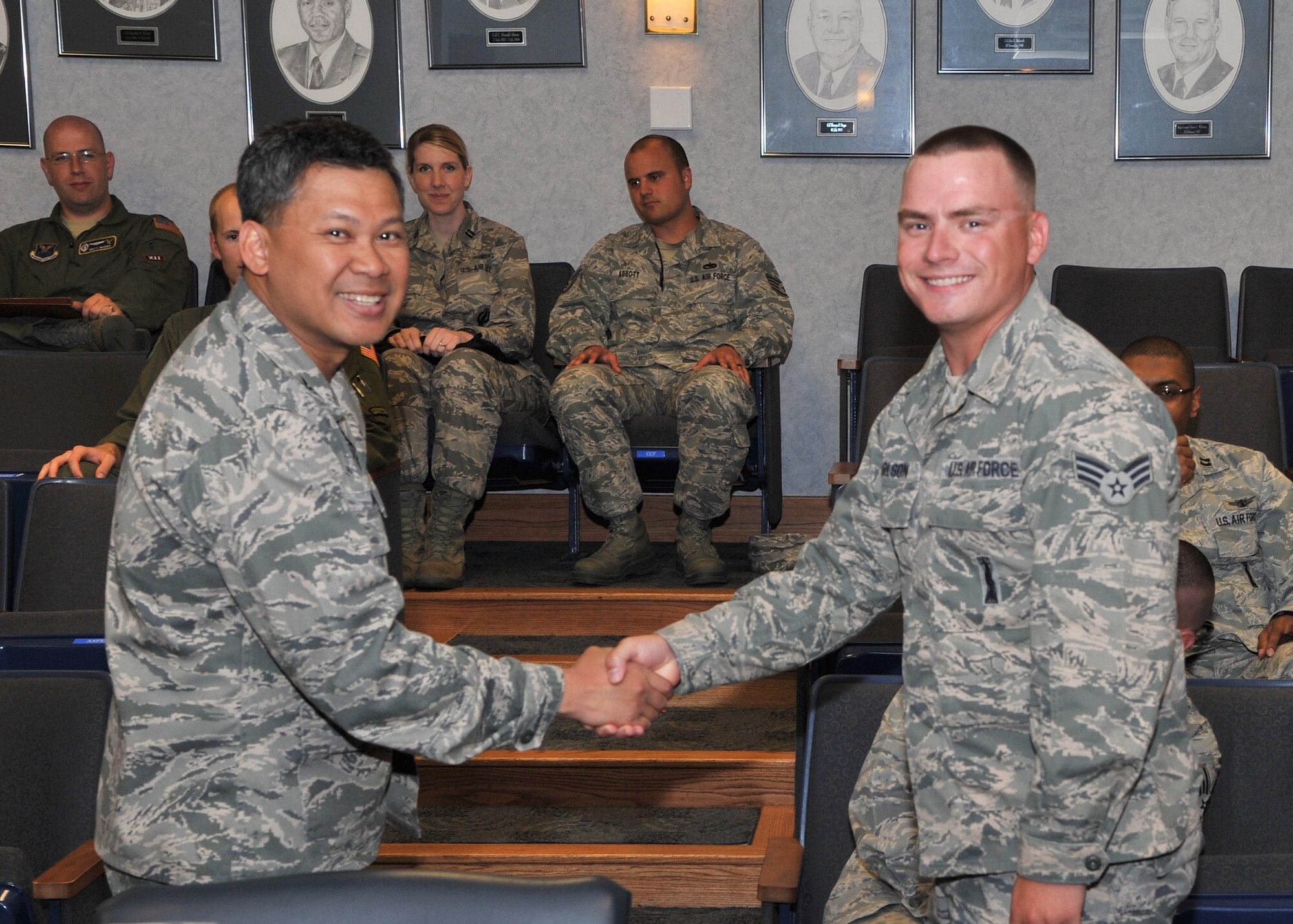 Col. H.B. Brual, 341st Missile Wing commander, left, presents Senior Airman Cory Carlson, 341st Missile Maintenance Squadron technician, with a coin recognizing Carlson’s 100th safe trip to the missile complex in a payload transporter June 27 in the wing conference room.  (U.S. Air Force photo/John Turner)