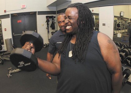 Fred Bray, fitness trainer with the 802nd Force Support Squadron, looks on as Jimmy Bailey curls a 35-pound dumbbell June 28 at the Chapparel Fitness Center. (U.S. Air Force Photo/Robbin Cresswell)