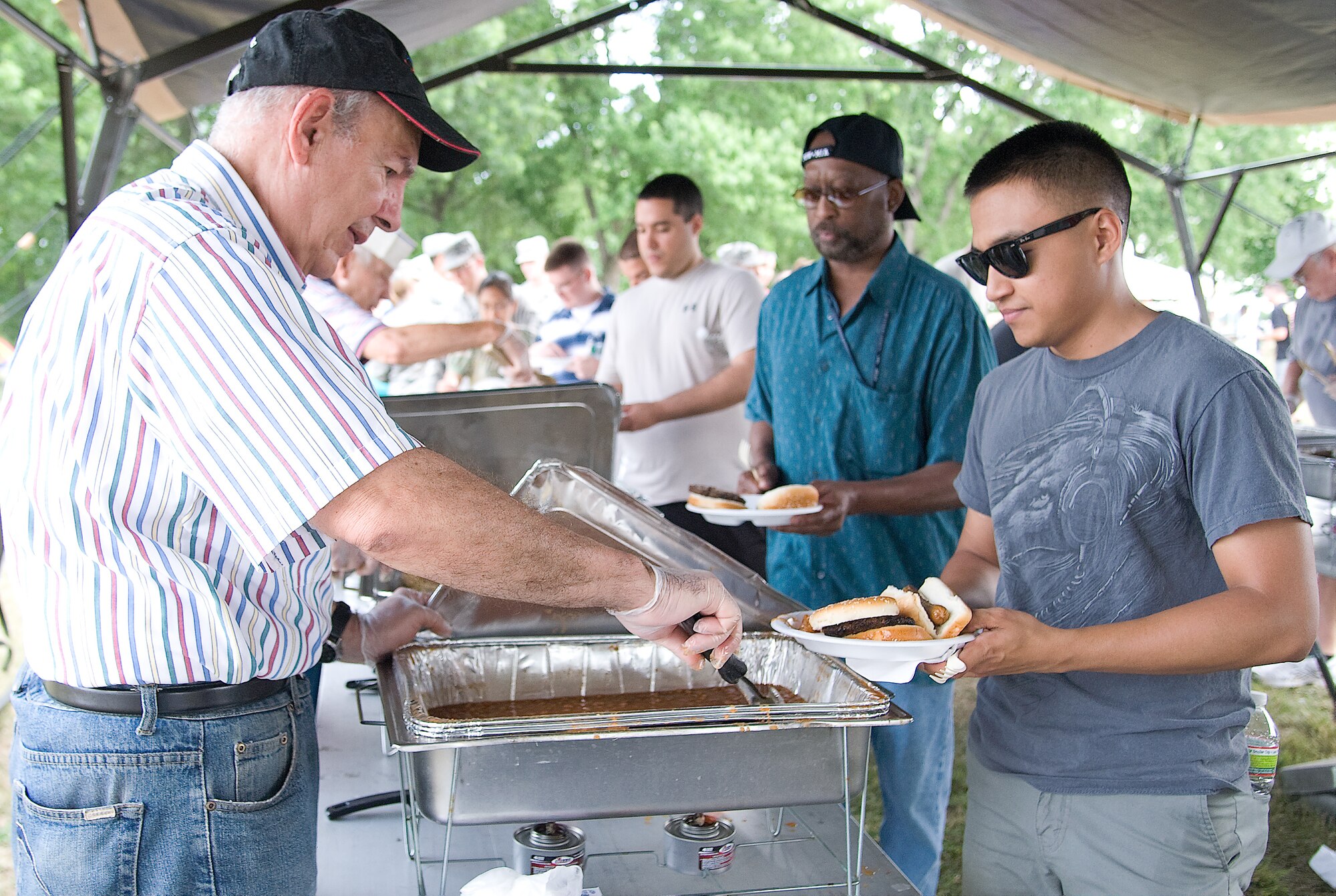 Retired Col. Frank Strapford dishes out food while Airman 1st Class Julian Cardenas goes through the line at the Wing Picnic July 3, 2012, at Dover Air Force Base, Del. The Wing Picnic was a base-wide event that celebrated the Fourth of July holiday. (U.S. Air Force photo by Adrian Rowan)