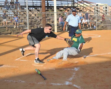 433rd Airlift Wing outfielder Ralph Ozuna slides into home plate as 453rd Electronic Warfare Squadron catcher Mike Hinger tags him in the first inning during Division III Recreational League play. Ozuna was ruled out at the plate. (U.S. Air Force photo/Alan Boedeker)