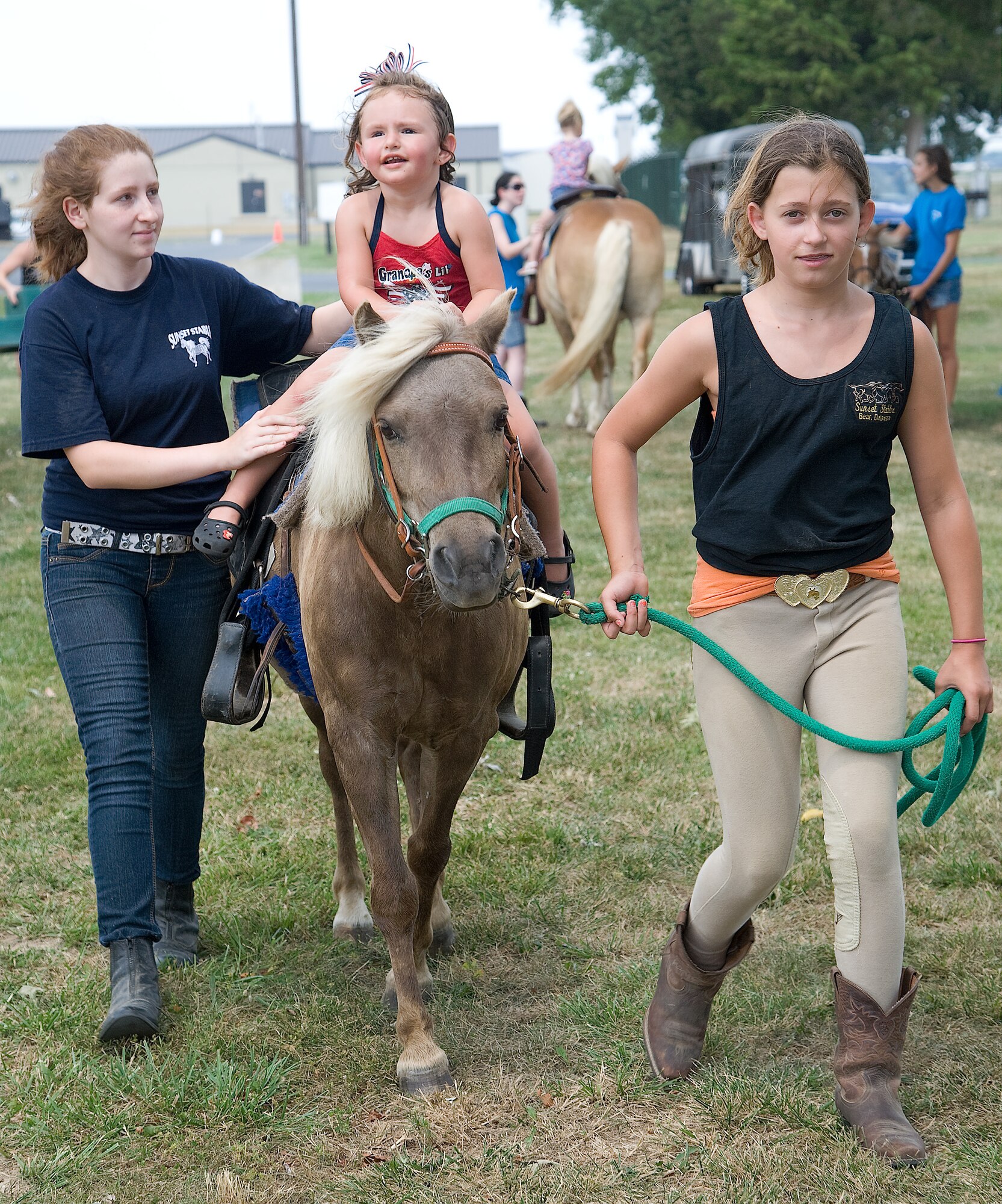 Ava Jean Corbett rides a pony as Maya Bonar helps to hold her on and Grace Silicato leads at the Wing Picnic July 3, 2012, at Dover Air Force Base, Del. Pony rides were just one of the many activities enjoyed at the base-wide event. (U.S. Air Force photo by Adrian Rowan)
