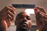 Staff Sgt. Christopher Barrow, 802nd Communications Squadron client system technician, inspects a stick of random access memory before installing it on a government computer June 14 at Joint Base San Antonio-Lackland. The squadron’s 36 client support technicians take care of computer problems for more than 9,000 PC users on base. (U.S. Air Force photo/Senior Airman Grovert Fuentes-Contreras)