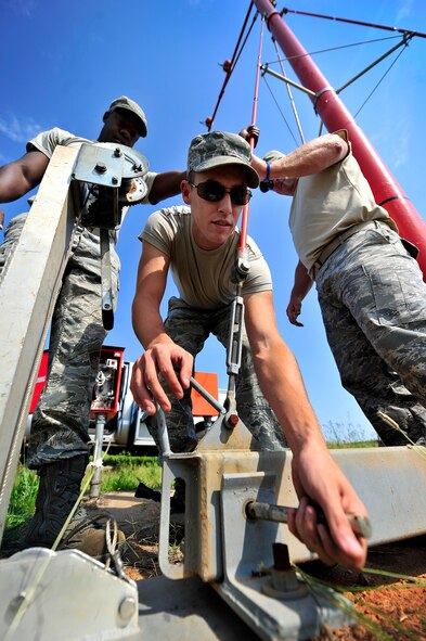 U.S. Air Force Airman 1st Class Justin Fleming, 20th Civil Engineer Squadron (center), puts the hinge pen to an airfield approach lighting stand back in while Staff Sgt. Julius Givens, (left), and Tech. Sgt. Daniel Harrington, both 20th CES, support the lighting system, Shaw Air Force Base, S.C., June 26, 2012. Harrington led a team of Airmen to repair several airfield lighting lamps and re-sync flashing approach lights. Shaw’s airfield lighting system is vital to all pilots who land and take off from the flightline. (U.S. Air Force photo by Senior Airman Kenny Holston/Released)