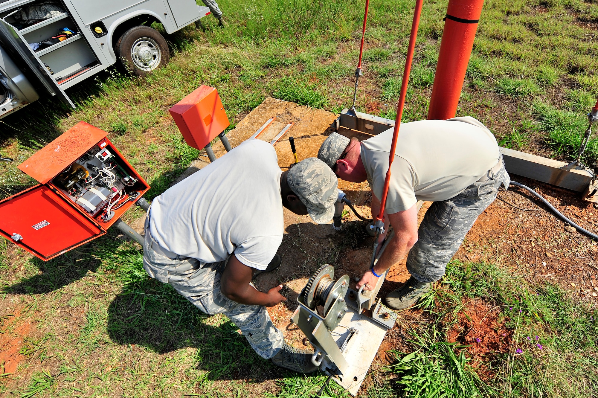 U.S. Air Force Staff Sgt. Julius Givens, (left), Tech. Sgt. Daniel Harrington, both 20th Civil Engineer Squadron, raise an airfield approach lighting stand after making repairs to a few of the lamps, Shaw Air Force Base, S.C., June 26, 2012. Harrington led a team of Airmen to repair several airfield lighting lamps and re-sync flashing approach lights. Shaw’s airfield lighting system is vital to all pilots who land and take off from the flightline. (U.S. Air Force photo by Senior Airman Kenny Holston/Released)