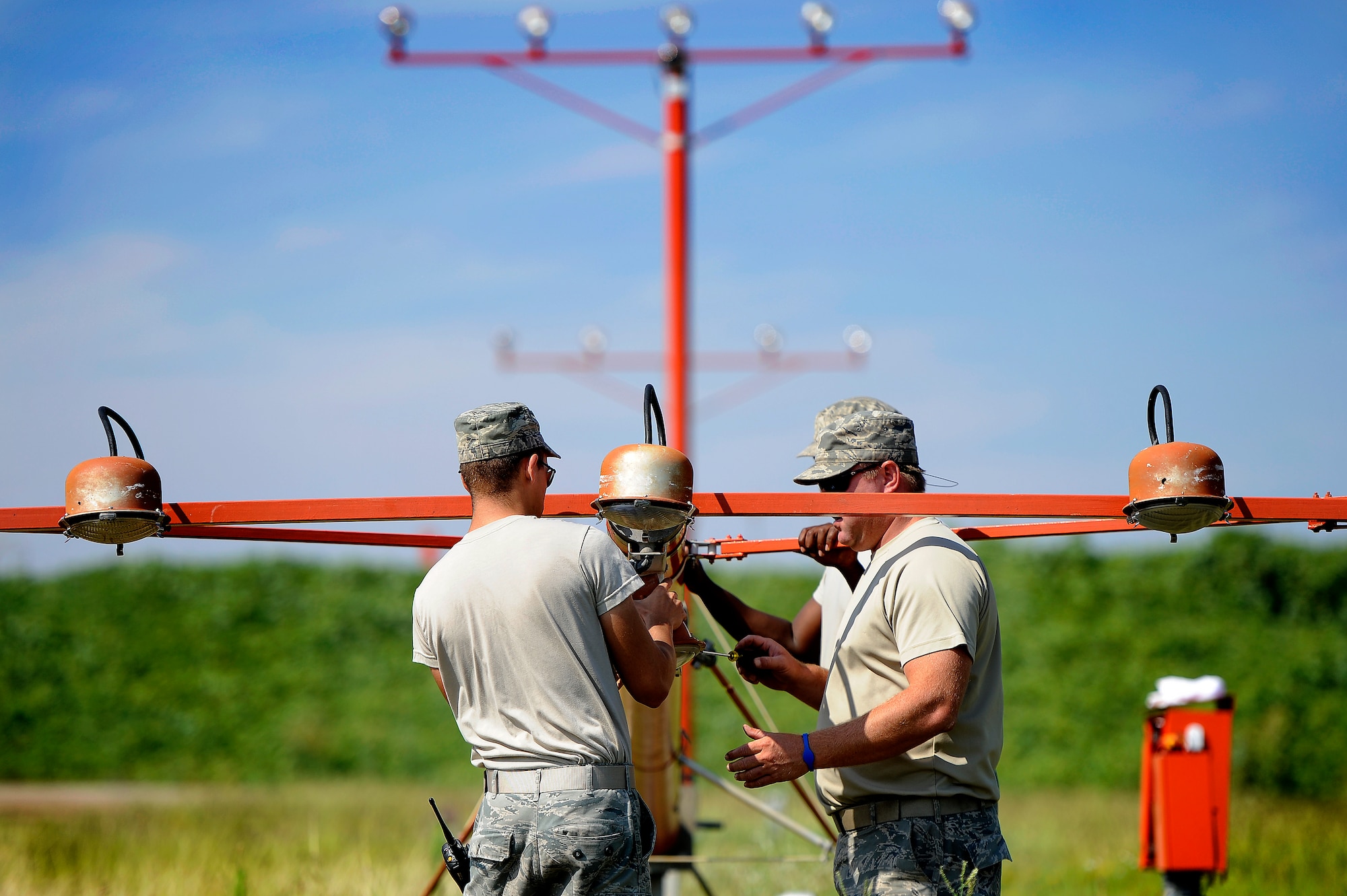 U.S. Air Force Airman 1st Class Justin Fleming, (left), and Tech. Sgt. Daniel Harrington, both 20th Civil Engineer Squadron, reattach an airfield lighting lamp to a lighting approach stand after repairing it, Shaw Air Force Base, S.C., June 26, 2012. Harrington led a team of Airmen to repair several airfield lighting lamps and re-sync flashing approach lights. Shaw’s airfield lighting system is vital to all pilots who land and take off from the flightline. (U.S. Air Force photo by Senior Airman Kenny Holston/Released)