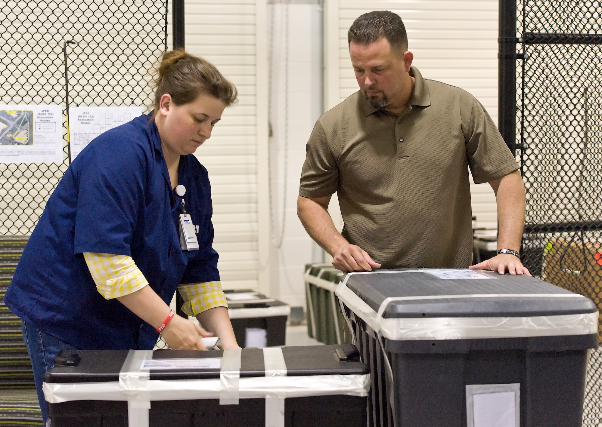 Megan Delzer, shipping lead coordinator, and Nelson Delgado, operations management specialist, both with the Joint Personal Effects Depot place shipping labels on personal effects footlockers June 29, 2012, at Dover Air Force Base, Del. Delgado validates the shipping paperwork on every footlocker prior to them leaving the JPED facility. (U.S. Air Force photo by Roland Balik)
