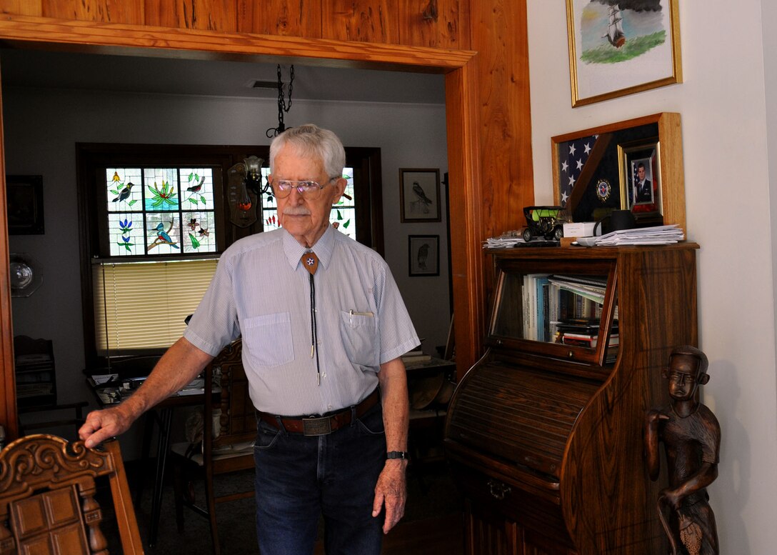 James Bollich, World War II veteran and Bataan Death March survivor, stands in his home next to a framed American flag that his grandson, an Airman, had flown over a U.S. military installation in his honor. Bollich spent three and a half years a Prisoner of War in Manchuria from 1942 until the end of WWII. (U.S. Air Force photo by Kate Blais)
