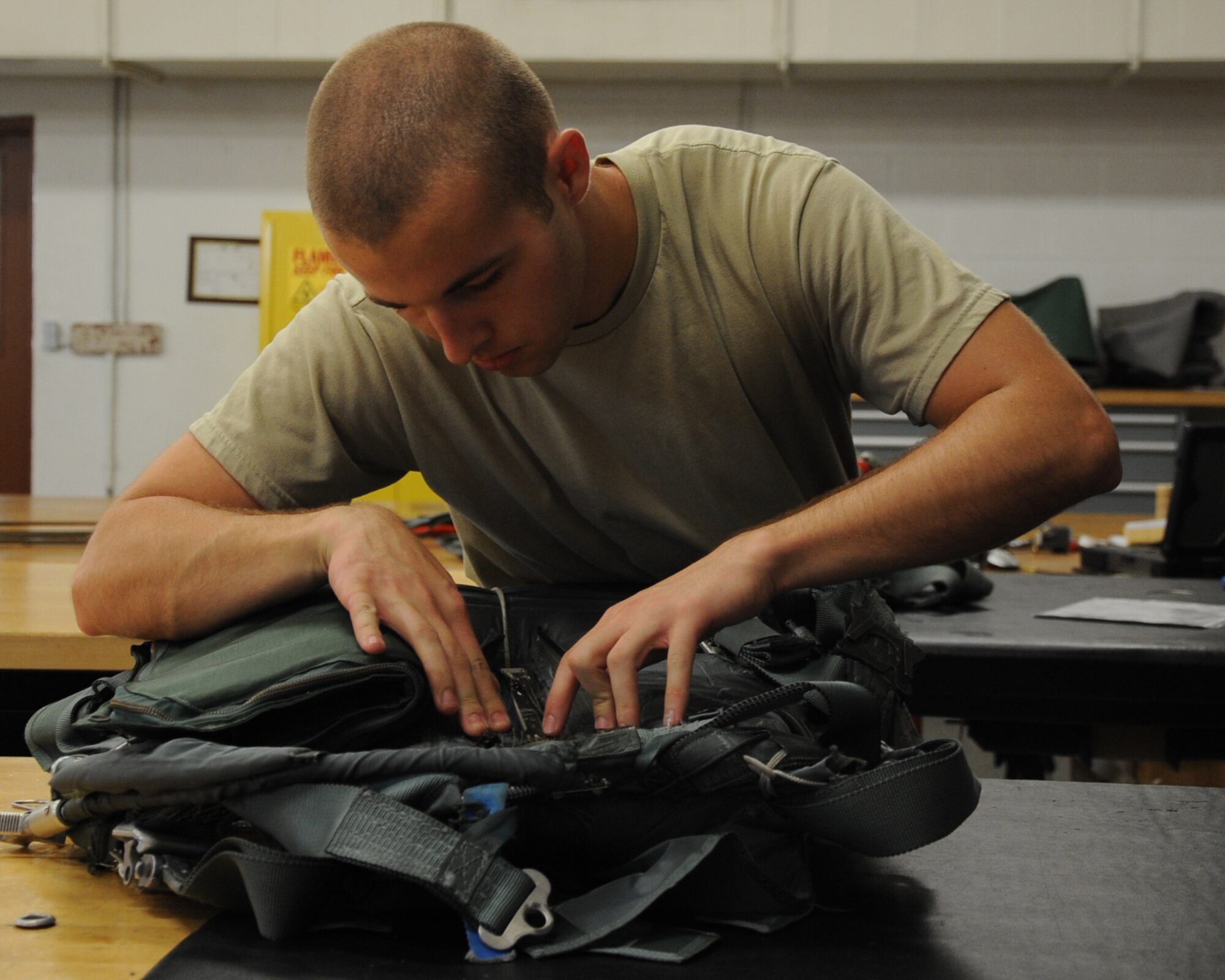 Airman 1st Class Jacob Rush, 2nd Operations Support Squadron aircrew flight equipment parachute packer, performs the final steps of packing a parachute on Barksdale Air Force Base, La., July 2. The AFE parachute shop packs, and repacks parachutes used by aircrew in the event on an egress. Each parachute is inspected every 180 days. (U.S. Air Force photo/Senior Airman Sean Martin)(RELEASED)
