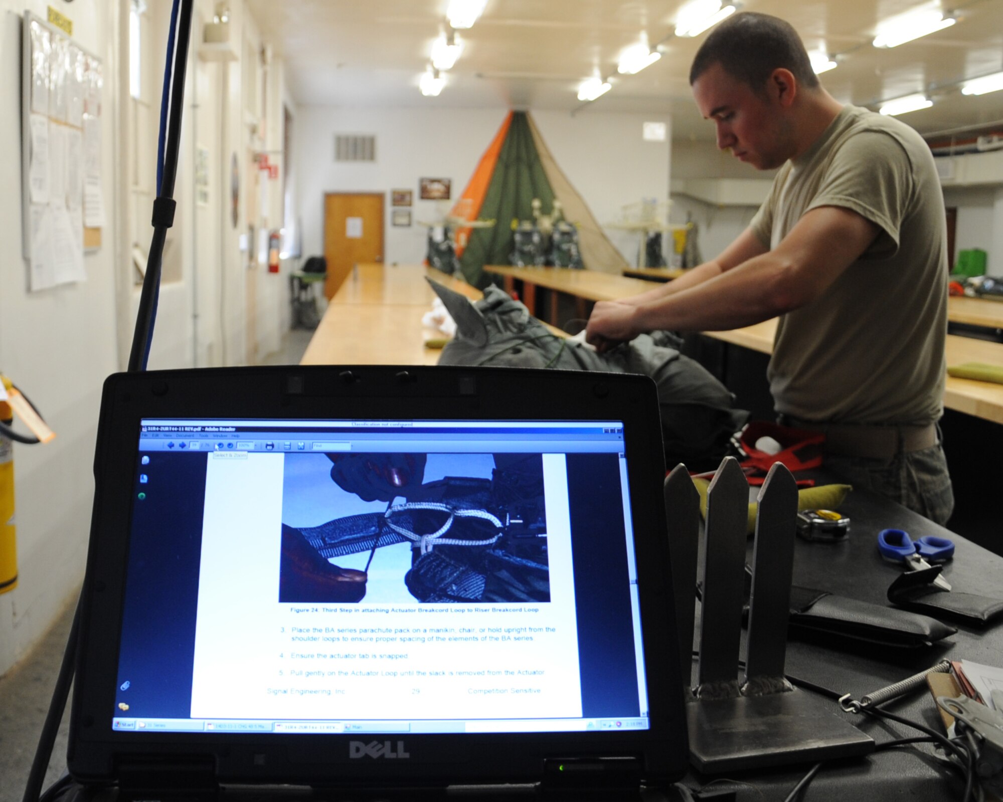 Airman 1st Class Ryan Lee, 2nd Operations Support Squadron aircrew flight equipment parachute shop, completes the final packing steps on a parachute while following the technical order shown in the foreground on Barksdale Air Force Base, La., July 2. A TO is followed step-by-step in order to ensure a parachute packed correctly and safely. (U.S. Air Force photo/Senior Airman Sean Martin)(RELEASED)
