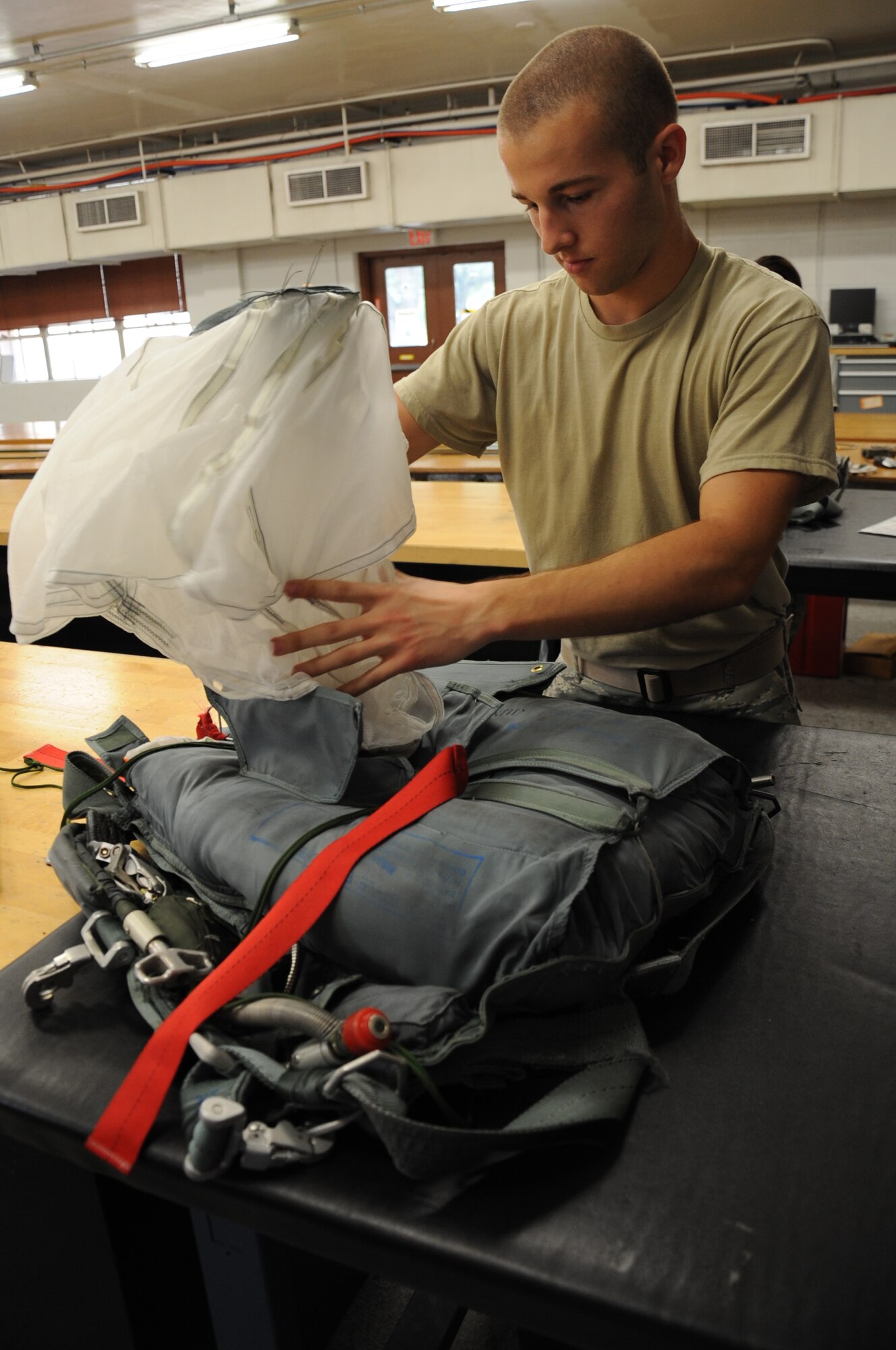 Airman 1st Class Jacob Rush, 2nd Operations Support Squadron aircrew flight equipment parachute shop, folds a parachute canopy on Barksdale Air Force Base, La., July 2. AFE personnel are responsible for packing, inspecting, and supplying aircrew with their survival parachutes. The parachutes are inspected every 180 days. (U.S. Air Force photo/Senior Airman Sean Martin)(RELEASED)
