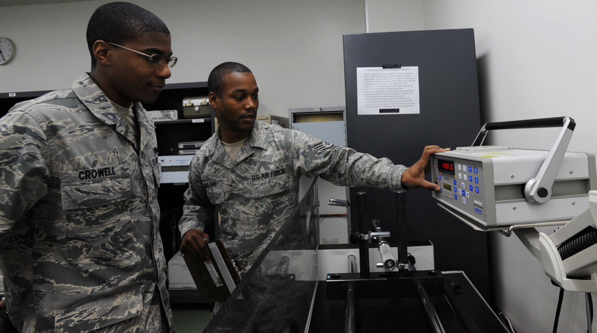 U.S. Air Force Staff Sgt. Edward Malone, right, 35th Maintenance Squadron laboratory quality assurance evaluator, shows Airman 1st Class Robert Crowell, 35th Maintenance Squadron laboratory apprentice, how to use a torque and force calibrator at Misawa Air Base, Japan, July 3, 2012. The calibrator generates, controls, measures and displays the rotational force applied to torque measuring tools up to 20,000 foot-pounds. (U.S. Air Force photo by Airman 1st Class Kenna Jackson/Released)