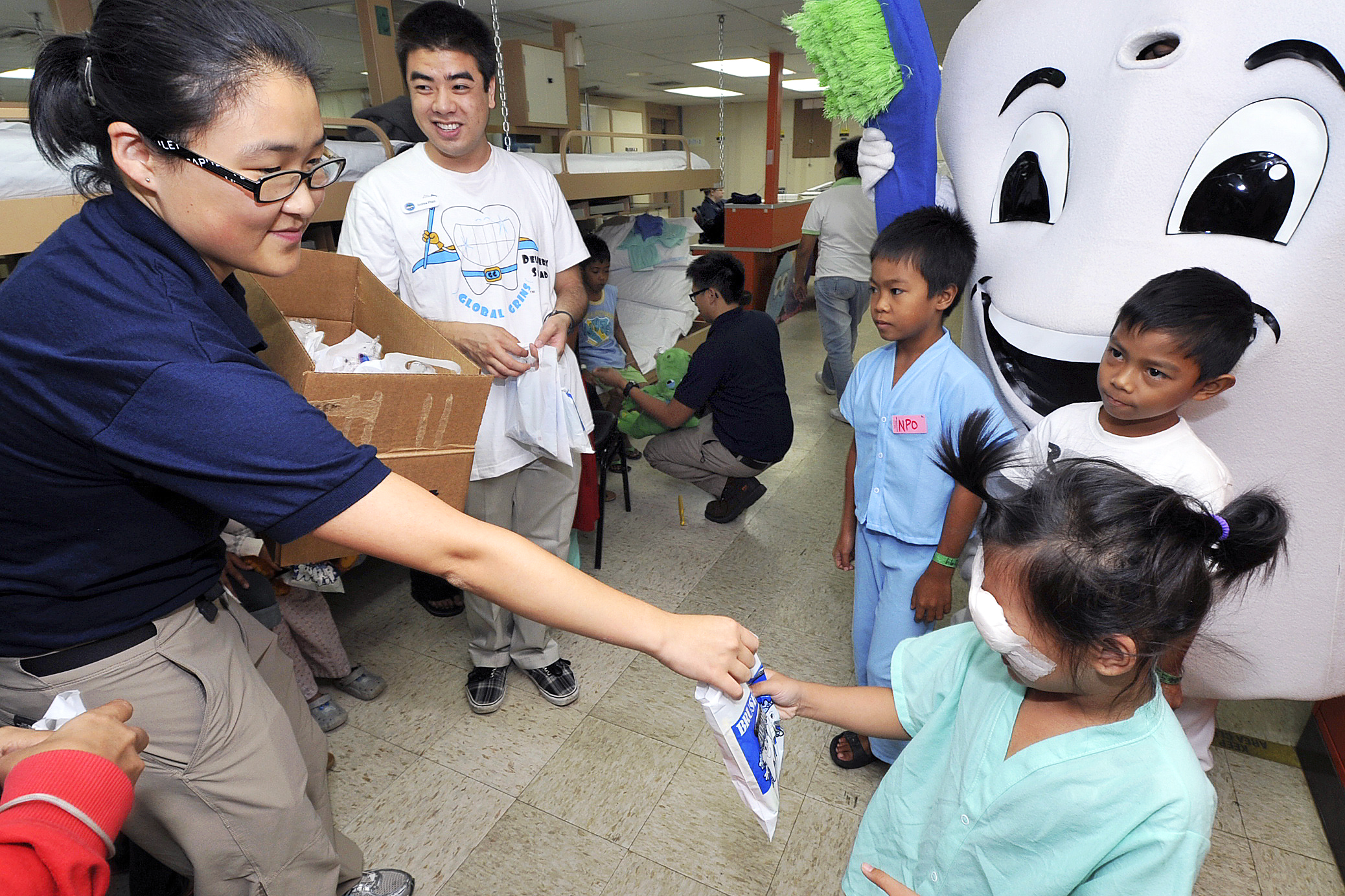 Eunice Lee, a volunteer, hands out dental care products to children in the  pediatrics ward aboard