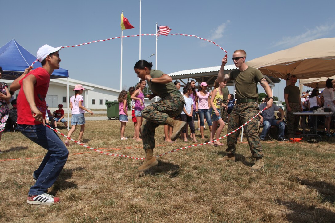 Staff Sergeant Dilia R. Molina, administration chief and Corporal Jaret W. Hubble, administration specialist with Black Sea Rotational Force 12 play jump rope with local Romanian children during an Independence Day celebration on Mihail Kogalniceanu, Romania July 4. Special guests of the event included approximately 200 local orphans from six homes in the Constanta, Romania area. Black Sea Rotational Force 12 is a Special-Purpose Marine Air-Ground Task Force with crisis response capabilities deployed to the region to enhance interoperability and promote regional stability.