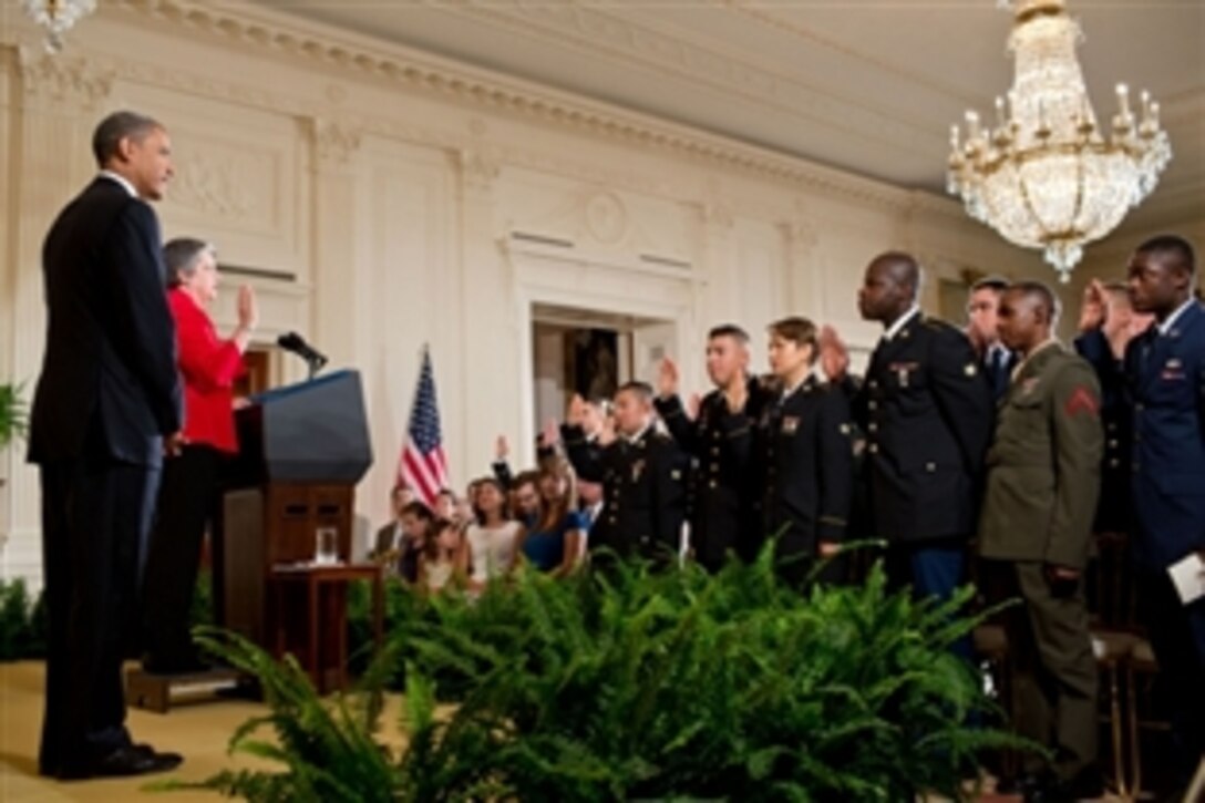 President Barack Obama listens as Homeland Security Secretary Janet Napolitano administers the Oath of Allegiance during a military naturalization ceremony for active-duty service members in the East Room of the White House, July 4, 2012. 