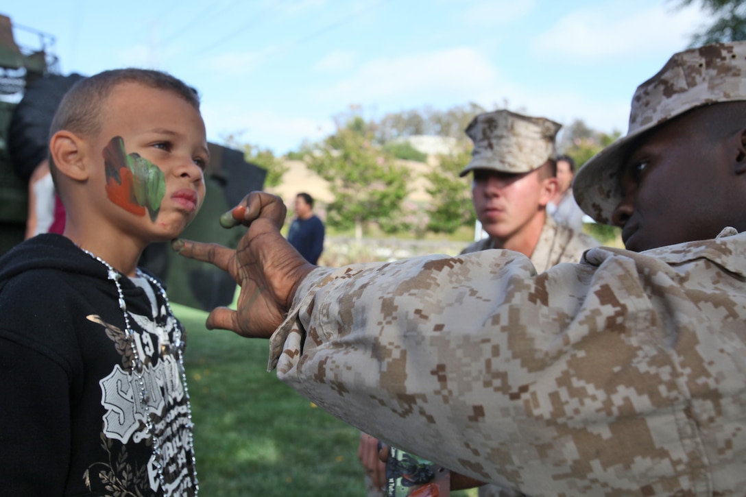 Lance Cpl. Dionte D. Jones, rifleman, Company L, Battalion Landing Team 3/5, 15th Marine Expeditionary Unit, paints camouflage on a child’s face at a static display in Laguna Hills, Calif., July 4. With help from Laguna Hills Team Darkhorse, a charitable organization that supports  BLT 3/5, the Marines and sailors displayed a Humvee, Landing Assault Vehicle, Landing Strike Vehicle, equipment and weapons before a fireworks display kicked off that evening. The servicemembers spent Independence Day educating and interacting with the Laguna Hills community to develop a deeper understanding of what the Marines and sailors do.