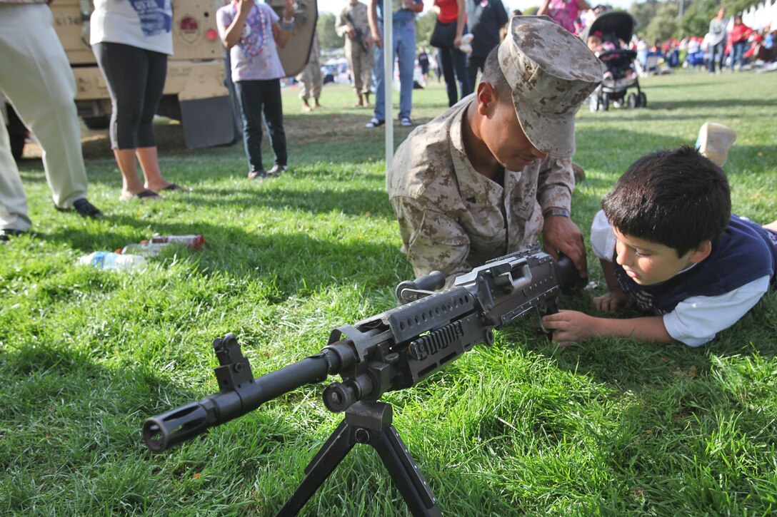 Cpl. Eric D. White, radio operator, Headquarters and Support Company, Battalion Landing Team 3/5, 15th Marine Expeditionary Unit, shows a child the M240B machine gun at a static display in Laguna Hills, Calif., July 4. With help from Laguna Hills Team Darkhorse, a charitable organization that supports BLT 3/5, the Marines and sailors displayed a Humvee, Landing Assault Vehicle, Landing Strike Vehicle, equipment and weapons before a fireworks display kicked off that evening. The servicemembers spent Independence Day educating and interacting with the Laguna Hills community to develop a deeper understanding of what the Marines and sailors do.
