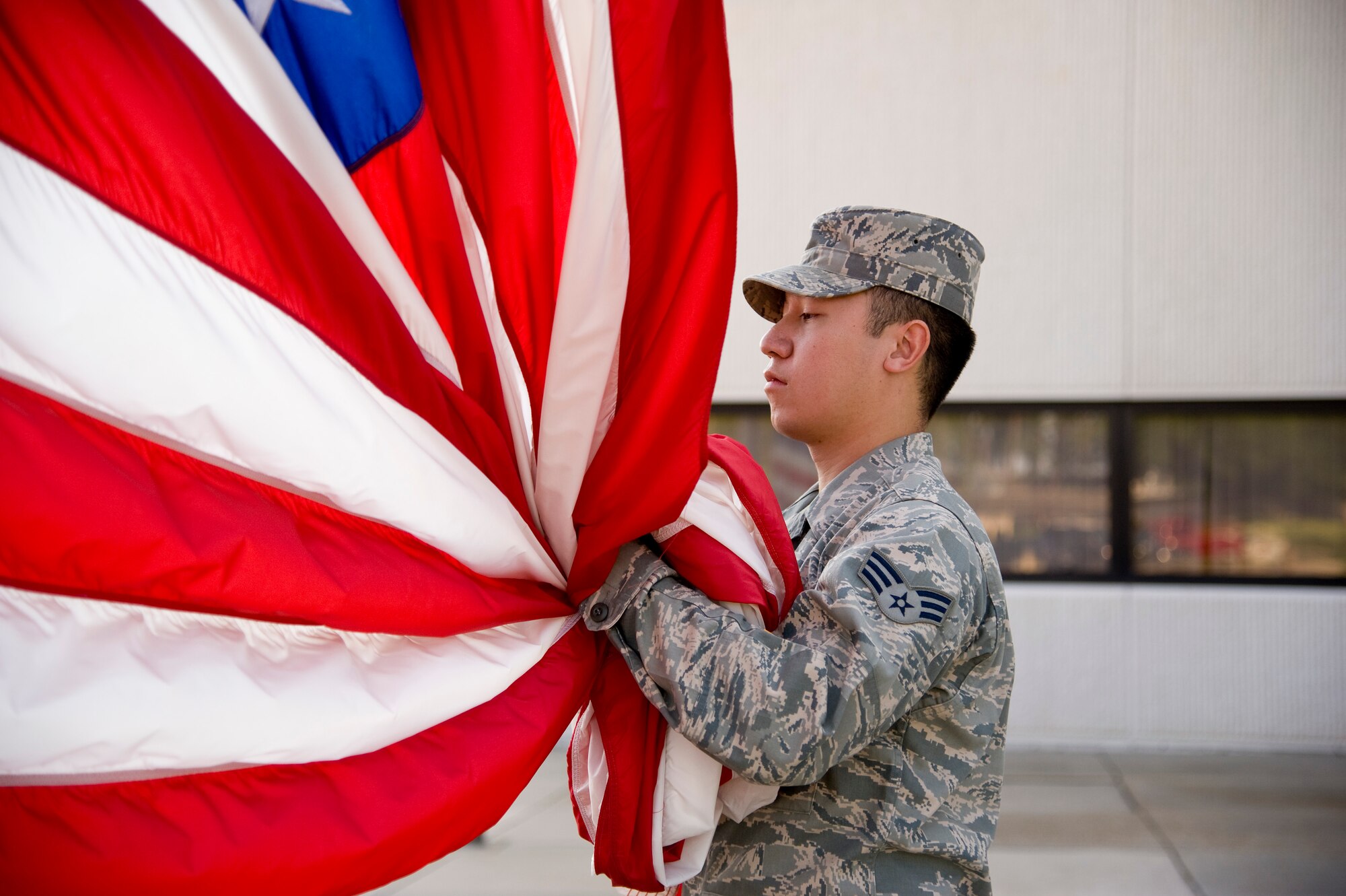 Senior Airman Bob Keophakdy, an air traffic controller from 1st Special Operations Support Squadron, secures the American flag as it is lowered during the weekly retreat ceremony in front of 1st Special Operations Wing headquarters at Hurlburt Field, Fla., June 27, 2012. The honor of performing retreat is rotated among different squadrons on base. (U.S. Air Force photo/Airman 1st Class Michelle Vickers)  (Released)

