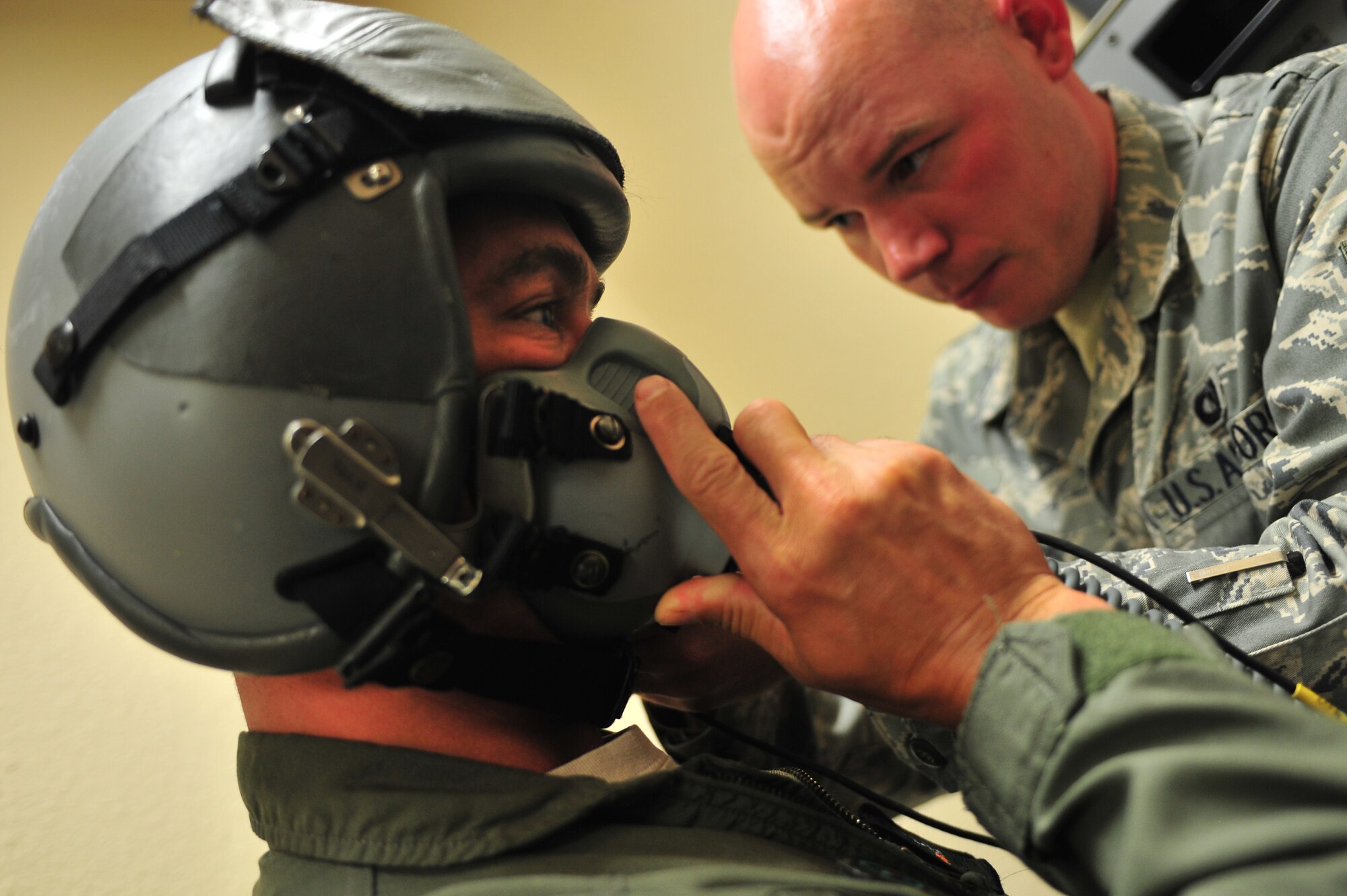 U.S. Air Force Senior Airman Nicholas Byars, 27th Special Operations Support Squadron aircrew flight equipment specialist, tightens the straps on a helmet for Capt. Jeremy Sparks, 16th Special Operations Squadron pilot, at Cannon Air Force Base, N.M., July 3, 2012. Aircrew flight equipment specialists inspect, maintain and adjust life support and survival gear for flight crew members assigned to Cannon. (U.S. Air Force photo by Airman 1st Class Eboni Reece)