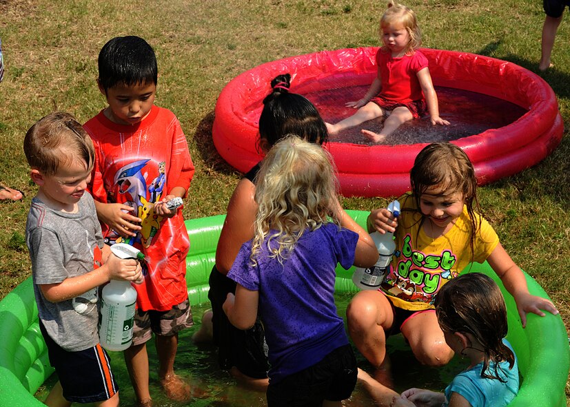 Dirt covered children rinse off in inflatable pools after a fossil excavation excercise during a Mud Day event at the library in Hurlburt Field, Fla., June. 30, 2012. Organizers offered children to small craft boats made of tinfoil and float them in a small inflatable pool. (U.S Air Force Photo/Airman 1st Class Nigel Sandridge/Released)