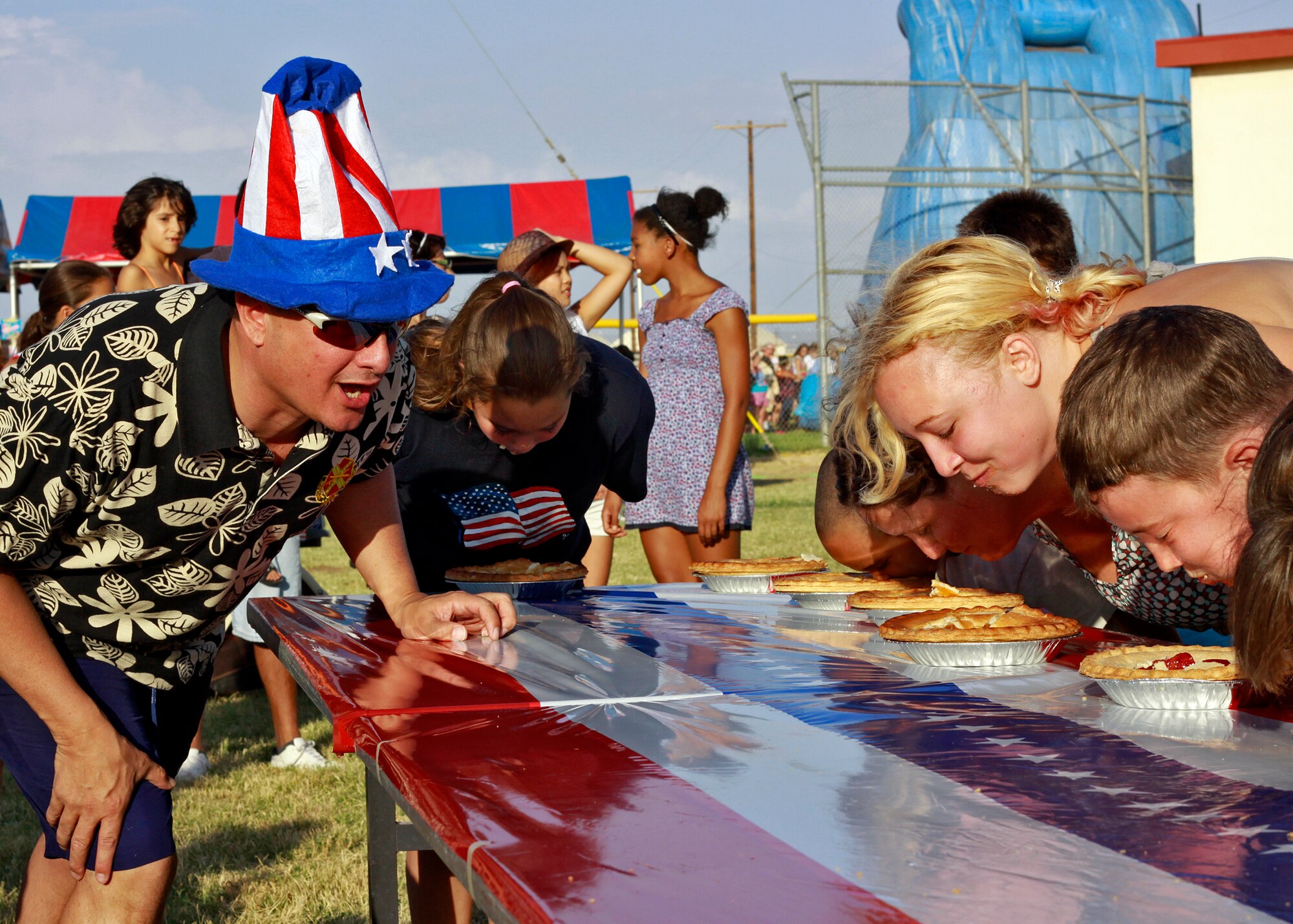 Carlos Bassut, 95th Force Support Squadron director, cheers on contestants during a pie-eating contest at the 2012 Summer Bash on July 4 at Wings and Roberts Field. (U.S. Air Force photo by Jet Fabara)