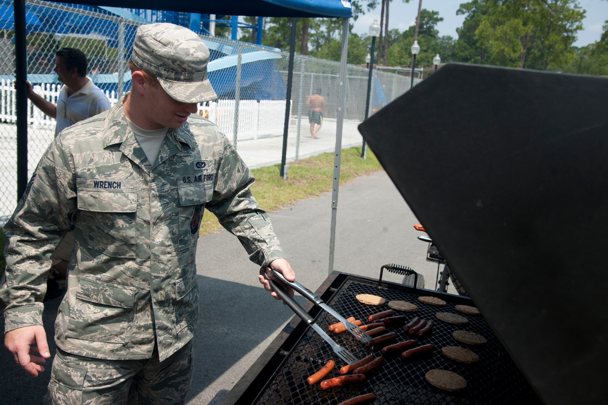 U.S. Air Force Airman 1st Class Dustin Wrench 23d Civil Engineer Squadron firefighter, grills hot dogs and burgers for an Independence Day celebration at Moody Air Force Base, Ga., July 4, 2012. Wrench was one of six volunteers from the 23d CES who helped with cooking, preparing and serving meals. (U.S. Air Force photo by Airman 1st Class Paul Francis/Released)