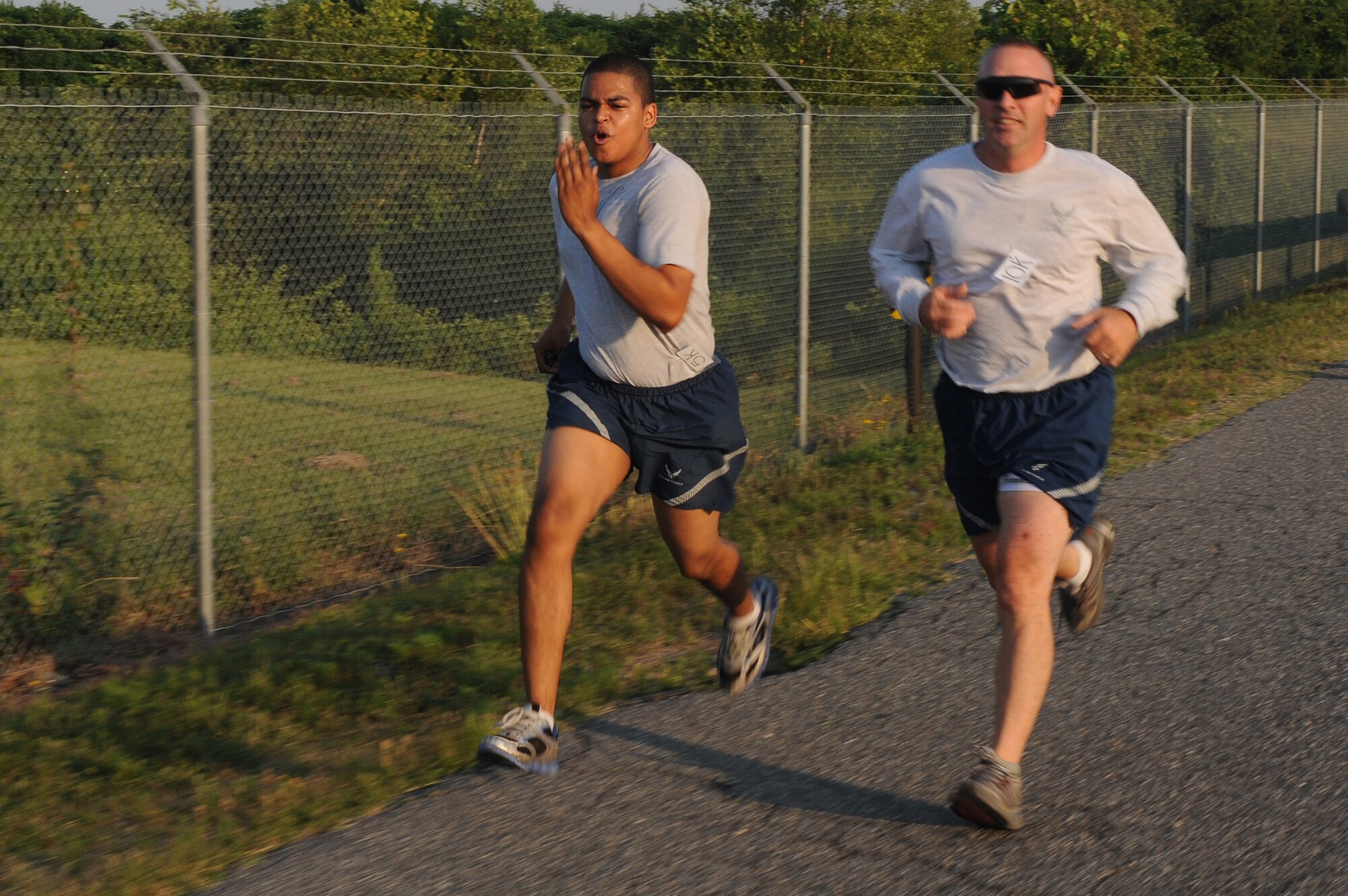 U.S. Air Force Airman 1st Class Michael Butts-Renteria (left) sprints past a competitor during the Freedom Run on Seymour Johnson Air Force Base, N.C., June 29, 2012. The run was held on Perimeter Road, and was an out and back course. Butts-Renteria, 4th Comptroller Squadron customer service technician, is from Havelock, N.C. (U.S. Air Force photo/Airman 1st Class John Nieves Camacho/Released)
